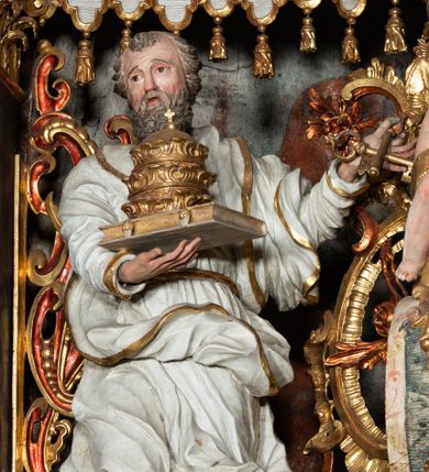 Zdjęcie nr 1: Rzeźba pełnoplastyczna, przyścienna, z tyłu, drążona, ustawiona na rzeźbionym fragmencie skały. Święty ukazany frontalnie, z prawą nogą ugiętą, opartą o skałę. Prawą rękę podtrzymuje przed sobą zamkniętą księgę z potrójną papieską tiarą; w lewej, wyciągniętej w bok ręce trzyma dwa skrzyżowane klucze. Twarz pociągła, o starczych rysach, niewielkich oczach, prostym długim nosie, niewielkich, rozchylonych ustach, okolona krótką, kręconą brodą. Włosy krótkie, kręcone, pukle po bokach i na czubku głowy. Święty ubrany w tunikę z kołnierzem, przepasaną w talii, marszczoną w gęste drobne fałdki, oraz płaszcz przerzucony przez lewe ramię i opadający gęstymi, grubymi fałdami, skręconej i ekspresyjnie rozwianej tkaniny na kolana i prawy bok. Polichromia naturalistyczna w odsłoniętych partiach ciała, szaty białe, atrybuty i detale stroju złocone.