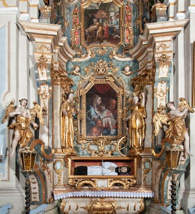 Zdjęcie nr 1: Ołtarz architektoniczny, jednoosiowy, jednokondygnacyjny ze zwieńczeniem, na cokole. Mensa drewniana umieszczona na drewnianej tumbie o wklęsło-wypukłych bokach. Antependium dekorowane rocaille’owym kartuszem z rytym gorejącym sercem, brzegi zdobione rocaille’em. W predelli przeszklona trumienka z figurą św. Jana Nepomucena, w profilowanej, złoconej ramie, na rocaillowej podstawie. Nastawa ujęta parami występujących do przodu filarów: wewnętrzne filary opięte pilastrami; zewnętrzne filary z wolutami zamiast trzonów, z figurami aniołów. Podpory dźwigają pełne belkowanie, przerwane nad polem środkowym. W polu nisza w kształcie stojącego prostokąta zamkniętego trójbocznie, w której obraz Święta Rodzina w profilowanej ramie. Przy filarach od wewnątrz rocaille’owe konsole z figurami św. Doroty i św. Katarzyny Aleksandryjskiej. Zwieńczenie w formie aedikuli zbliżonej do kwadratu o fantazyjnym wklęsło-wypukłym zamknięciu; ujęte pilastrami przechodzącymi w spływy wolutowe, opadające na belkowanie, tworzące postumenty dla figur św. Stefana i św. Emeryka. W polu zwieńczenia obraz z przedstawieniem Świętej Rodziny przy pracy, w kształcie kwadratu o wklęsłych narożach, w profilowanej ramie. Zwieńczenie zamknięte glorią promienistą z literami IHS w otoczeniu obłoków; na osi pilastrów rokokowe wazony z różami.W partii cokołów kanony w rocaille’owych ramach. Trzony pilastrów i woluty dekorowane rocaille’owymi płycinami, we fryzie rocaille. Nisza w polu środkowym ujęta rocaille’ami, zwieńczona mitrą książęcą, flankowana przez parę uskrzydlonych główek anielskich. Woluty zwieńczenia dekorowane motywami rocaille’ów. Rama obrazu w polu ujęta małżowiną, ornamentem roślinnym i rocaille’ami. Struktura marmoryzowana w odcieniu jasnoniebieskim, podpory, tumba i cokoły w odcieniu kości słoniowej; ornamentyka i profile złocone.