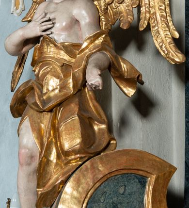 Zdjęcie nr 28: Ołtarz architektoniczny, jednoosiowy, jednokondygnacyjny ze zwieńczeniem, na cokole. Mensa drewniana umieszczona na drewnianej tumbie o wklęsło-wypukłych bokach. Antependium dekorowane rocaille’owym kartuszem z rytym gorejącym sercem, brzegi zdobione rocaille’em. W predelli przeszklona trumienka z figurą św. Jana Nepomucena, w profilowanej, złoconej ramie, na rocaillowej podstawie. Nastawa ujęta parami występujących do przodu filarów: wewnętrzne filary opięte pilastrami; zewnętrzne filary z wolutami zamiast trzonów, z figurami aniołów. Podpory dźwigają pełne belkowanie, przerwane nad polem środkowym. W polu nisza w kształcie stojącego prostokąta zamkniętego trójbocznie, w której obraz Święta Rodzina w profilowanej ramie. Przy filarach od wewnątrz rocaille’owe konsole z figurami św. Doroty i św. Katarzyny Aleksandryjskiej. Zwieńczenie w formie aedikuli zbliżonej do kwadratu o fantazyjnym wklęsło-wypukłym zamknięciu; ujęte pilastrami przechodzącymi w spływy wolutowe, opadające na belkowanie, tworzące postumenty dla figur św. Stefana i św. Emeryka. W polu zwieńczenia obraz z przedstawieniem Świętej Rodziny przy pracy, w kształcie kwadratu o wklęsłych narożach, w profilowanej ramie. Zwieńczenie zamknięte glorią promienistą z literami IHS w otoczeniu obłoków; na osi pilastrów rokokowe wazony z różami.W partii cokołów kanony w rocaille’owych ramach. Trzony pilastrów i woluty dekorowane rocaille’owymi płycinami, we fryzie rocaille. Nisza w polu środkowym ujęta rocaille’ami, zwieńczona mitrą książęcą, flankowana przez parę uskrzydlonych główek anielskich. Woluty zwieńczenia dekorowane motywami rocaille’ów. Rama obrazu w polu ujęta małżowiną, ornamentem roślinnym i rocaille’ami. Struktura marmoryzowana w odcieniu jasnoniebieskim, podpory, tumba i cokoły w odcieniu kości słoniowej; ornamentyka i profile złocone.