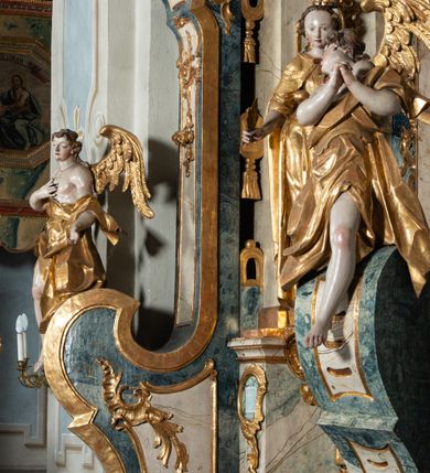 Zdjęcie nr 13: Ołtarz architektoniczny, jednoosiowy, jednokondygnacyjny ze zwieńczeniem, na cokole. Mensa drewniana umieszczona na drewnianej tumbie o wklęsło-wypukłych bokach. Antependium dekorowane rocaille’owym kartuszem z rytym gorejącym sercem, brzegi zdobione rocaille’em. W predelli przeszklona trumienka z figurą św. Jana Nepomucena, w profilowanej, złoconej ramie, na rocaillowej podstawie. Nastawa ujęta parami występujących do przodu filarów: wewnętrzne filary opięte pilastrami; zewnętrzne filary z wolutami zamiast trzonów, z figurami aniołów. Podpory dźwigają pełne belkowanie, przerwane nad polem środkowym. W polu nisza w kształcie stojącego prostokąta zamkniętego trójbocznie, w której obraz Święta Rodzina w profilowanej ramie. Przy filarach od wewnątrz rocaille’owe konsole z figurami św. Doroty i św. Katarzyny Aleksandryjskiej. Zwieńczenie w formie aedikuli zbliżonej do kwadratu o fantazyjnym wklęsło-wypukłym zamknięciu; ujęte pilastrami przechodzącymi w spływy wolutowe, opadające na belkowanie, tworzące postumenty dla figur św. Stefana i św. Emeryka. W polu zwieńczenia obraz z przedstawieniem Świętej Rodziny przy pracy, w kształcie kwadratu o wklęsłych narożach, w profilowanej ramie. Zwieńczenie zamknięte glorią promienistą z literami IHS w otoczeniu obłoków; na osi pilastrów rokokowe wazony z różami.W partii cokołów kanony w rocaille’owych ramach. Trzony pilastrów i woluty dekorowane rocaille’owymi płycinami, we fryzie rocaille. Nisza w polu środkowym ujęta rocaille’ami, zwieńczona mitrą książęcą, flankowana przez parę uskrzydlonych główek anielskich. Woluty zwieńczenia dekorowane motywami rocaille’ów. Rama obrazu w polu ujęta małżowiną, ornamentem roślinnym i rocaille’ami. Struktura marmoryzowana w odcieniu jasnoniebieskim, podpory, tumba i cokoły w odcieniu kości słoniowej; ornamentyka i profile złocone.