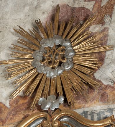 Zdjęcie nr 38: Ołtarz architektoniczny, jednoosiowy, jednokondygnacyjny ze zwieńczeniem, na cokole. Mensa drewniana umieszczona na drewnianej tumbie o wklęsło-wypukłych bokach. Antependium dekorowane rocaille’owym kartuszem z rytym gorejącym sercem, brzegi zdobione rocaille’em. W predelli przeszklona trumienka z figurą św. Jana Nepomucena, w profilowanej, złoconej ramie, na rocaillowej podstawie. Nastawa ujęta parami występujących do przodu filarów: wewnętrzne filary opięte pilastrami; zewnętrzne filary z wolutami zamiast trzonów, z figurami aniołów. Podpory dźwigają pełne belkowanie, przerwane nad polem środkowym. W polu nisza w kształcie stojącego prostokąta zamkniętego trójbocznie, w której obraz Święta Rodzina w profilowanej ramie. Przy filarach od wewnątrz rocaille’owe konsole z figurami św. Doroty i św. Katarzyny Aleksandryjskiej. Zwieńczenie w formie aedikuli zbliżonej do kwadratu o fantazyjnym wklęsło-wypukłym zamknięciu; ujęte pilastrami przechodzącymi w spływy wolutowe, opadające na belkowanie, tworzące postumenty dla figur św. Stefana i św. Emeryka. W polu zwieńczenia obraz z przedstawieniem Świętej Rodziny przy pracy, w kształcie kwadratu o wklęsłych narożach, w profilowanej ramie. Zwieńczenie zamknięte glorią promienistą z literami IHS w otoczeniu obłoków; na osi pilastrów rokokowe wazony z różami.W partii cokołów kanony w rocaille’owych ramach. Trzony pilastrów i woluty dekorowane rocaille’owymi płycinami, we fryzie rocaille. Nisza w polu środkowym ujęta rocaille’ami, zwieńczona mitrą książęcą, flankowana przez parę uskrzydlonych główek anielskich. Woluty zwieńczenia dekorowane motywami rocaille’ów. Rama obrazu w polu ujęta małżowiną, ornamentem roślinnym i rocaille’ami. Struktura marmoryzowana w odcieniu jasnoniebieskim, podpory, tumba i cokoły w odcieniu kości słoniowej; ornamentyka i profile złocone.