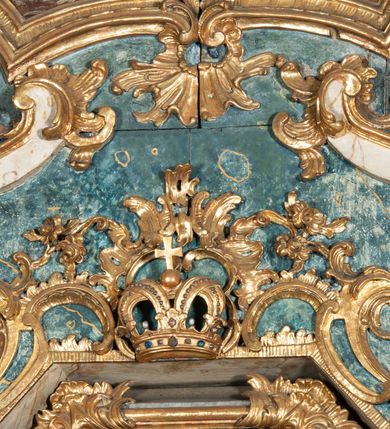 Zdjęcie nr 35: Ołtarz architektoniczny, jednoosiowy, jednokondygnacyjny ze zwieńczeniem, na cokole. Mensa drewniana umieszczona na drewnianej tumbie o wklęsło-wypukłych bokach. Antependium dekorowane rocaille’owym kartuszem z rytym gorejącym sercem, brzegi zdobione rocaille’em. W predelli przeszklona trumienka z figurą św. Jana Nepomucena, w profilowanej, złoconej ramie, na rocaillowej podstawie. Nastawa ujęta parami występujących do przodu filarów: wewnętrzne filary opięte pilastrami; zewnętrzne filary z wolutami zamiast trzonów, z figurami aniołów. Podpory dźwigają pełne belkowanie, przerwane nad polem środkowym. W polu nisza w kształcie stojącego prostokąta zamkniętego trójbocznie, w której obraz Święta Rodzina w profilowanej ramie. Przy filarach od wewnątrz rocaille’owe konsole z figurami św. Doroty i św. Katarzyny Aleksandryjskiej. Zwieńczenie w formie aedikuli zbliżonej do kwadratu o fantazyjnym wklęsło-wypukłym zamknięciu; ujęte pilastrami przechodzącymi w spływy wolutowe, opadające na belkowanie, tworzące postumenty dla figur św. Stefana i św. Emeryka. W polu zwieńczenia obraz z przedstawieniem Świętej Rodziny przy pracy, w kształcie kwadratu o wklęsłych narożach, w profilowanej ramie. Zwieńczenie zamknięte glorią promienistą z literami IHS w otoczeniu obłoków; na osi pilastrów rokokowe wazony z różami.W partii cokołów kanony w rocaille’owych ramach. Trzony pilastrów i woluty dekorowane rocaille’owymi płycinami, we fryzie rocaille. Nisza w polu środkowym ujęta rocaille’ami, zwieńczona mitrą książęcą, flankowana przez parę uskrzydlonych główek anielskich. Woluty zwieńczenia dekorowane motywami rocaille’ów. Rama obrazu w polu ujęta małżowiną, ornamentem roślinnym i rocaille’ami. Struktura marmoryzowana w odcieniu jasnoniebieskim, podpory, tumba i cokoły w odcieniu kości słoniowej; ornamentyka i profile złocone.