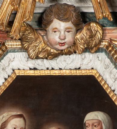 Zdjęcie nr 52: Ołtarz architektoniczny, trójosiowy, z wydzieloną częścią cokołową z bramkami bocznymi, jednokondygnacyjny, ze zwieńczeniem. Mensa drewniana z portatylem z marmuru dębnickiego, umieszczona na drewnianej, prostopadłościennej skrzyni.  Antepedium w kształcie leżącego prostokąta, ujęte profilowaną ramą dekorowaną liśćmi akantu i perełkowaniem. W polu płaskorzeźbione przedstawienie baranka leżącego na krzyżu, na obłoku, ujęte parą liści akantu oraz wicią roślinną z kwiatami i kiściami winogron. 
Na mensie tabernakulum z Tronem Łaski w formie prostopadłościanu na cokole, o wypukłej ściance frontowej, ujęte spływami wolutowymi podtrzymującymi niepełne belkowanie, wyłamane po środku łukiem półkolistym. Na froncie obrotowa nisza ujęta obramieniem w kształcie stojącego prostokąta zamkniętego łukiem nadwieszonym. W niszy ryte przedstawienie kielicha z Eucharystią w glorii, na obłoku, całość w rocaillowej ramie. Powyżej tron wystawienia z cokołem dekorowanym rocaille’em i parą ornamentalnych świeczników; ujęty parą kolumn dźwigających imposty. Podpory dżwigają rocaillowe kabłąki tworzące baldachim, na którego szczycie figurka baranka eucharystycznego leżącego na księdze. Ścianka w formie zbliżonej do stojącego prostokąta ujęta rocaille. Tabernakulum i tron ujęte okazałymi spływami wolutowymi z rocaillowymi uszami oraz na zakończeniach u dołu dwiema rzeźbami klęczących, adorujących aniołów.
Osie nastawy wydzielone w osiach skrajnych parą kolumn o skręconych trzonach i korynckich kapitelach umieszczonych na tle pilastrów, w osiach wewnętrznych parą pilastrów o trzonach w formie wolut z puttami z puttami, podtrzymywaną przez kariatydy w formie okazałych figur uskrzydlonych aniołów. Podpory wspierają pełne belkowanie z profilowanym gzymsem, występujące nad nimi, przerwane nad polem środkowym. W polu środkowym nisza ze sklepieniem kolebkowym wspartym na dwóch filarach i pilastrach. W głębi niszy obraz Św. Bartłomiej w profilowanej ramie w kształcie stojącego prostokąta zamkniętego łukiem odcinkowym. Na podniebiu niszy obraz Męczeństwo św. Bartłomieja w kształcie leżącego prostokąta ujętego niesymetrycznym obramieniem z motywem rocaille’ów. Nisza flankowana z figurami św. Stefana i św. Emeryka umieszczonymi na konsolach, na tle pilastrów. Pola retabulum w osiach skrajnych wklęsłe, między podporami prześwity z figurami św. Piotra i św. Pawła. W partii wysokiego cokołu bramki ujęte od zewnątrz wklęsłymi filarami podtrzymującymi belkowanie, wejścia z drzwiczkami w kształcie stojącego prostokąta zamkniętego łukiem półkolistym z obrazami przedstawiającymi Mojżesza i Aarona. Zwieńczenie w formie aedikuli ujętej pilastrami wspierającymi przerwane belkowanie oraz fantazyjnymi spływami wolutowymi, spływającymi na wewnętrzne podpory, przyjmując formę przerwanego przyczółka, na którym dwa putta i dwie figury siedzących aniołów. W osiach zewnętrznych podpór dwa putta siedzące kanelowanych postumentach i obłokach, prawe przytrzymuje skórę (atrybut św. Bartłomieja). W polu zwieńczenia obraz Św. Anna Samotrzeć w kształcie wydłużonego ośmioboku, w ornamentalnej ramie. Całość zwieńczona rzeźbioną półpostacią Boga Ojca pośród obłoków ukazanego w glorii promienistej. Drzwi do bramek flankowane liściastymi festonami, powyżej tarcze ujęte liśćmi laurowymi, zwieńczone koroną z klejnotem; lewa z klejnotem w postaci łabędzia z napisem: SOLI/ DEO/GLORIA, prawa z postacią ludzką z napisem: SOLI DEO HONOR. Woluty i fryz dekorowane motywami rocaille’ów oraz uskrzydlonymi główkami anielskimi. Osie boczne wypełnione ażurowymi rocaille’ami z gałązkami różanymi oraz ornamentem małżowinowo-chrząstkowym, belkowanie z podwieszonym lambrekinem z chwostami. Skręcone trzony kolumn zdobione wicią z winnej latorośli. Archiwolta nad polem środkowym dekorowana rocaille’em, rocaille’owym kartuszem i lambrekinem z chwostami. Woluty zwieńczenia, pilastry i naroża pola obrazowego dekorowane motywami rocaille’ów. 
Nastawa marmoryzowana w odcieniu jasnoszarym, profile marmoryzowane w kolorze jasnoróżowym, ornamenty i obramienia złocone.