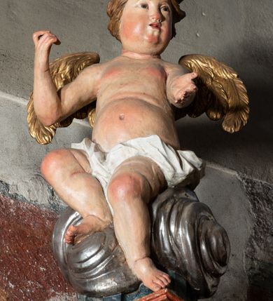 Zdjęcie nr 59: Ołtarz architektoniczny, trójosiowy, z wydzieloną częścią cokołową z bramkami bocznymi, jednokondygnacyjny, ze zwieńczeniem. Mensa drewniana z portatylem z marmuru dębnickiego, umieszczona na drewnianej, prostopadłościennej skrzyni.  Antepedium w kształcie leżącego prostokąta, ujęte profilowaną ramą dekorowaną liśćmi akantu i perełkowaniem. W polu płaskorzeźbione przedstawienie baranka leżącego na krzyżu, na obłoku, ujęte parą liści akantu oraz wicią roślinną z kwiatami i kiściami winogron. 
Na mensie tabernakulum z Tronem Łaski w formie prostopadłościanu na cokole, o wypukłej ściance frontowej, ujęte spływami wolutowymi podtrzymującymi niepełne belkowanie, wyłamane po środku łukiem półkolistym. Na froncie obrotowa nisza ujęta obramieniem w kształcie stojącego prostokąta zamkniętego łukiem nadwieszonym. W niszy ryte przedstawienie kielicha z Eucharystią w glorii, na obłoku, całość w rocaillowej ramie. Powyżej tron wystawienia z cokołem dekorowanym rocaille’em i parą ornamentalnych świeczników; ujęty parą kolumn dźwigających imposty. Podpory dżwigają rocaillowe kabłąki tworzące baldachim, na którego szczycie figurka baranka eucharystycznego leżącego na księdze. Ścianka w formie zbliżonej do stojącego prostokąta ujęta rocaille. Tabernakulum i tron ujęte okazałymi spływami wolutowymi z rocaillowymi uszami oraz na zakończeniach u dołu dwiema rzeźbami klęczących, adorujących aniołów.
Osie nastawy wydzielone w osiach skrajnych parą kolumn o skręconych trzonach i korynckich kapitelach umieszczonych na tle pilastrów, w osiach wewnętrznych parą pilastrów o trzonach w formie wolut z puttami z puttami, podtrzymywaną przez kariatydy w formie okazałych figur uskrzydlonych aniołów. Podpory wspierają pełne belkowanie z profilowanym gzymsem, występujące nad nimi, przerwane nad polem środkowym. W polu środkowym nisza ze sklepieniem kolebkowym wspartym na dwóch filarach i pilastrach. W głębi niszy obraz Św. Bartłomiej w profilowanej ramie w kształcie stojącego prostokąta zamkniętego łukiem odcinkowym. Na podniebiu niszy obraz Męczeństwo św. Bartłomieja w kształcie leżącego prostokąta ujętego niesymetrycznym obramieniem z motywem rocaille’ów. Nisza flankowana z figurami św. Stefana i św. Emeryka umieszczonymi na konsolach, na tle pilastrów. Pola retabulum w osiach skrajnych wklęsłe, między podporami prześwity z figurami św. Piotra i św. Pawła. W partii wysokiego cokołu bramki ujęte od zewnątrz wklęsłymi filarami podtrzymującymi belkowanie, wejścia z drzwiczkami w kształcie stojącego prostokąta zamkniętego łukiem półkolistym z obrazami przedstawiającymi Mojżesza i Aarona. Zwieńczenie w formie aedikuli ujętej pilastrami wspierającymi przerwane belkowanie oraz fantazyjnymi spływami wolutowymi, spływającymi na wewnętrzne podpory, przyjmując formę przerwanego przyczółka, na którym dwa putta i dwie figury siedzących aniołów. W osiach zewnętrznych podpór dwa putta siedzące kanelowanych postumentach i obłokach, prawe przytrzymuje skórę (atrybut św. Bartłomieja). W polu zwieńczenia obraz Św. Anna Samotrzeć w kształcie wydłużonego ośmioboku, w ornamentalnej ramie. Całość zwieńczona rzeźbioną półpostacią Boga Ojca pośród obłoków ukazanego w glorii promienistej. Drzwi do bramek flankowane liściastymi festonami, powyżej tarcze ujęte liśćmi laurowymi, zwieńczone koroną z klejnotem; lewa z klejnotem w postaci łabędzia z napisem: SOLI/ DEO/GLORIA, prawa z postacią ludzką z napisem: SOLI DEO HONOR. Woluty i fryz dekorowane motywami rocaille’ów oraz uskrzydlonymi główkami anielskimi. Osie boczne wypełnione ażurowymi rocaille’ami z gałązkami różanymi oraz ornamentem małżowinowo-chrząstkowym, belkowanie z podwieszonym lambrekinem z chwostami. Skręcone trzony kolumn zdobione wicią z winnej latorośli. Archiwolta nad polem środkowym dekorowana rocaille’em, rocaille’owym kartuszem i lambrekinem z chwostami. Woluty zwieńczenia, pilastry i naroża pola obrazowego dekorowane motywami rocaille’ów. 
Nastawa marmoryzowana w odcieniu jasnoszarym, profile marmoryzowane w kolorze jasnoróżowym, ornamenty i obramienia złocone.