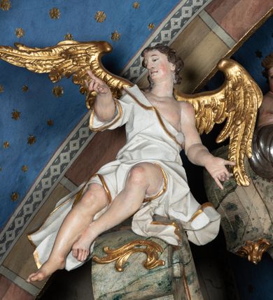 Zdjęcie nr 38: Ołtarz architektoniczny, trójosiowy, z wydzieloną częścią cokołową z bramkami bocznymi, jednokondygnacyjny, ze zwieńczeniem. Mensa drewniana z portatylem z marmuru dębnickiego, umieszczona na drewnianej, prostopadłościennej skrzyni.  Antepedium w kształcie leżącego prostokąta, ujęte profilowaną ramą dekorowaną liśćmi akantu i perełkowaniem. W polu płaskorzeźbione przedstawienie baranka leżącego na krzyżu, na obłoku, ujęte parą liści akantu oraz wicią roślinną z kwiatami i kiściami winogron. 
Na mensie tabernakulum z Tronem Łaski w formie prostopadłościanu na cokole, o wypukłej ściance frontowej, ujęte spływami wolutowymi podtrzymującymi niepełne belkowanie, wyłamane po środku łukiem półkolistym. Na froncie obrotowa nisza ujęta obramieniem w kształcie stojącego prostokąta zamkniętego łukiem nadwieszonym. W niszy ryte przedstawienie kielicha z Eucharystią w glorii, na obłoku, całość w rocaillowej ramie. Powyżej tron wystawienia z cokołem dekorowanym rocaille’em i parą ornamentalnych świeczników; ujęty parą kolumn dźwigających imposty. Podpory dżwigają rocaillowe kabłąki tworzące baldachim, na którego szczycie figurka baranka eucharystycznego leżącego na księdze. Ścianka w formie zbliżonej do stojącego prostokąta ujęta rocaille. Tabernakulum i tron ujęte okazałymi spływami wolutowymi z rocaillowymi uszami oraz na zakończeniach u dołu dwiema rzeźbami klęczących, adorujących aniołów.
Osie nastawy wydzielone w osiach skrajnych parą kolumn o skręconych trzonach i korynckich kapitelach umieszczonych na tle pilastrów, w osiach wewnętrznych parą pilastrów o trzonach w formie wolut z puttami z puttami, podtrzymywaną przez kariatydy w formie okazałych figur uskrzydlonych aniołów. Podpory wspierają pełne belkowanie z profilowanym gzymsem, występujące nad nimi, przerwane nad polem środkowym. W polu środkowym nisza ze sklepieniem kolebkowym wspartym na dwóch filarach i pilastrach. W głębi niszy obraz Św. Bartłomiej w profilowanej ramie w kształcie stojącego prostokąta zamkniętego łukiem odcinkowym. Na podniebiu niszy obraz Męczeństwo św. Bartłomieja w kształcie leżącego prostokąta ujętego niesymetrycznym obramieniem z motywem rocaille’ów. Nisza flankowana z figurami św. Stefana i św. Emeryka umieszczonymi na konsolach, na tle pilastrów. Pola retabulum w osiach skrajnych wklęsłe, między podporami prześwity z figurami św. Piotra i św. Pawła. W partii wysokiego cokołu bramki ujęte od zewnątrz wklęsłymi filarami podtrzymującymi belkowanie, wejścia z drzwiczkami w kształcie stojącego prostokąta zamkniętego łukiem półkolistym z obrazami przedstawiającymi Mojżesza i Aarona. Zwieńczenie w formie aedikuli ujętej pilastrami wspierającymi przerwane belkowanie oraz fantazyjnymi spływami wolutowymi, spływającymi na wewnętrzne podpory, przyjmując formę przerwanego przyczółka, na którym dwa putta i dwie figury siedzących aniołów. W osiach zewnętrznych podpór dwa putta siedzące kanelowanych postumentach i obłokach, prawe przytrzymuje skórę (atrybut św. Bartłomieja). W polu zwieńczenia obraz Św. Anna Samotrzeć w kształcie wydłużonego ośmioboku, w ornamentalnej ramie. Całość zwieńczona rzeźbioną półpostacią Boga Ojca pośród obłoków ukazanego w glorii promienistej. Drzwi do bramek flankowane liściastymi festonami, powyżej tarcze ujęte liśćmi laurowymi, zwieńczone koroną z klejnotem; lewa z klejnotem w postaci łabędzia z napisem: SOLI/ DEO/GLORIA, prawa z postacią ludzką z napisem: SOLI DEO HONOR. Woluty i fryz dekorowane motywami rocaille’ów oraz uskrzydlonymi główkami anielskimi. Osie boczne wypełnione ażurowymi rocaille’ami z gałązkami różanymi oraz ornamentem małżowinowo-chrząstkowym, belkowanie z podwieszonym lambrekinem z chwostami. Skręcone trzony kolumn zdobione wicią z winnej latorośli. Archiwolta nad polem środkowym dekorowana rocaille’em, rocaille’owym kartuszem i lambrekinem z chwostami. Woluty zwieńczenia, pilastry i naroża pola obrazowego dekorowane motywami rocaille’ów. 
Nastawa marmoryzowana w odcieniu jasnoszarym, profile marmoryzowane w kolorze jasnoróżowym, ornamenty i obramienia złocone.