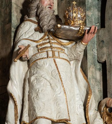 Zdjęcie nr 28: Ołtarz architektoniczny, trójosiowy, z wydzieloną częścią cokołową z bramkami bocznymi, jednokondygnacyjny, ze zwieńczeniem. Mensa drewniana z portatylem z marmuru dębnickiego, umieszczona na drewnianej, prostopadłościennej skrzyni.  Antepedium w kształcie leżącego prostokąta, ujęte profilowaną ramą dekorowaną liśćmi akantu i perełkowaniem. W polu płaskorzeźbione przedstawienie baranka leżącego na krzyżu, na obłoku, ujęte parą liści akantu oraz wicią roślinną z kwiatami i kiściami winogron. 
Na mensie tabernakulum z Tronem Łaski w formie prostopadłościanu na cokole, o wypukłej ściance frontowej, ujęte spływami wolutowymi podtrzymującymi niepełne belkowanie, wyłamane po środku łukiem półkolistym. Na froncie obrotowa nisza ujęta obramieniem w kształcie stojącego prostokąta zamkniętego łukiem nadwieszonym. W niszy ryte przedstawienie kielicha z Eucharystią w glorii, na obłoku, całość w rocaillowej ramie. Powyżej tron wystawienia z cokołem dekorowanym rocaille’em i parą ornamentalnych świeczników; ujęty parą kolumn dźwigających imposty. Podpory dżwigają rocaillowe kabłąki tworzące baldachim, na którego szczycie figurka baranka eucharystycznego leżącego na księdze. Ścianka w formie zbliżonej do stojącego prostokąta ujęta rocaille. Tabernakulum i tron ujęte okazałymi spływami wolutowymi z rocaillowymi uszami oraz na zakończeniach u dołu dwiema rzeźbami klęczących, adorujących aniołów.
Osie nastawy wydzielone w osiach skrajnych parą kolumn o skręconych trzonach i korynckich kapitelach umieszczonych na tle pilastrów, w osiach wewnętrznych parą pilastrów o trzonach w formie wolut z puttami z puttami, podtrzymywaną przez kariatydy w formie okazałych figur uskrzydlonych aniołów. Podpory wspierają pełne belkowanie z profilowanym gzymsem, występujące nad nimi, przerwane nad polem środkowym. W polu środkowym nisza ze sklepieniem kolebkowym wspartym na dwóch filarach i pilastrach. W głębi niszy obraz Św. Bartłomiej w profilowanej ramie w kształcie stojącego prostokąta zamkniętego łukiem odcinkowym. Na podniebiu niszy obraz Męczeństwo św. Bartłomieja w kształcie leżącego prostokąta ujętego niesymetrycznym obramieniem z motywem rocaille’ów. Nisza flankowana z figurami św. Stefana i św. Emeryka umieszczonymi na konsolach, na tle pilastrów. Pola retabulum w osiach skrajnych wklęsłe, między podporami prześwity z figurami św. Piotra i św. Pawła. W partii wysokiego cokołu bramki ujęte od zewnątrz wklęsłymi filarami podtrzymującymi belkowanie, wejścia z drzwiczkami w kształcie stojącego prostokąta zamkniętego łukiem półkolistym z obrazami przedstawiającymi Mojżesza i Aarona. Zwieńczenie w formie aedikuli ujętej pilastrami wspierającymi przerwane belkowanie oraz fantazyjnymi spływami wolutowymi, spływającymi na wewnętrzne podpory, przyjmując formę przerwanego przyczółka, na którym dwa putta i dwie figury siedzących aniołów. W osiach zewnętrznych podpór dwa putta siedzące kanelowanych postumentach i obłokach, prawe przytrzymuje skórę (atrybut św. Bartłomieja). W polu zwieńczenia obraz Św. Anna Samotrzeć w kształcie wydłużonego ośmioboku, w ornamentalnej ramie. Całość zwieńczona rzeźbioną półpostacią Boga Ojca pośród obłoków ukazanego w glorii promienistej. Drzwi do bramek flankowane liściastymi festonami, powyżej tarcze ujęte liśćmi laurowymi, zwieńczone koroną z klejnotem; lewa z klejnotem w postaci łabędzia z napisem: SOLI/ DEO/GLORIA, prawa z postacią ludzką z napisem: SOLI DEO HONOR. Woluty i fryz dekorowane motywami rocaille’ów oraz uskrzydlonymi główkami anielskimi. Osie boczne wypełnione ażurowymi rocaille’ami z gałązkami różanymi oraz ornamentem małżowinowo-chrząstkowym, belkowanie z podwieszonym lambrekinem z chwostami. Skręcone trzony kolumn zdobione wicią z winnej latorośli. Archiwolta nad polem środkowym dekorowana rocaille’em, rocaille’owym kartuszem i lambrekinem z chwostami. Woluty zwieńczenia, pilastry i naroża pola obrazowego dekorowane motywami rocaille’ów. 
Nastawa marmoryzowana w odcieniu jasnoszarym, profile marmoryzowane w kolorze jasnoróżowym, ornamenty i obramienia złocone.