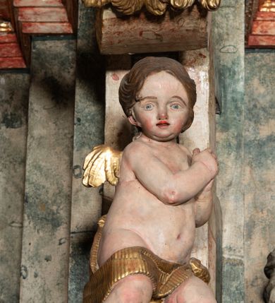 Zdjęcie nr 56: Ołtarz architektoniczny, trójosiowy, z wydzieloną częścią cokołową z bramkami bocznymi, jednokondygnacyjny, ze zwieńczeniem. Mensa drewniana z portatylem z marmuru dębnickiego, umieszczona na drewnianej, prostopadłościennej skrzyni.  Antepedium w kształcie leżącego prostokąta, ujęte profilowaną ramą dekorowaną liśćmi akantu i perełkowaniem. W polu płaskorzeźbione przedstawienie baranka leżącego na krzyżu, na obłoku, ujęte parą liści akantu oraz wicią roślinną z kwiatami i kiściami winogron. 
Na mensie tabernakulum z Tronem Łaski w formie prostopadłościanu na cokole, o wypukłej ściance frontowej, ujęte spływami wolutowymi podtrzymującymi niepełne belkowanie, wyłamane po środku łukiem półkolistym. Na froncie obrotowa nisza ujęta obramieniem w kształcie stojącego prostokąta zamkniętego łukiem nadwieszonym. W niszy ryte przedstawienie kielicha z Eucharystią w glorii, na obłoku, całość w rocaillowej ramie. Powyżej tron wystawienia z cokołem dekorowanym rocaille’em i parą ornamentalnych świeczników; ujęty parą kolumn dźwigających imposty. Podpory dżwigają rocaillowe kabłąki tworzące baldachim, na którego szczycie figurka baranka eucharystycznego leżącego na księdze. Ścianka w formie zbliżonej do stojącego prostokąta ujęta rocaille. Tabernakulum i tron ujęte okazałymi spływami wolutowymi z rocaillowymi uszami oraz na zakończeniach u dołu dwiema rzeźbami klęczących, adorujących aniołów.
Osie nastawy wydzielone w osiach skrajnych parą kolumn o skręconych trzonach i korynckich kapitelach umieszczonych na tle pilastrów, w osiach wewnętrznych parą pilastrów o trzonach w formie wolut z puttami z puttami, podtrzymywaną przez kariatydy w formie okazałych figur uskrzydlonych aniołów. Podpory wspierają pełne belkowanie z profilowanym gzymsem, występujące nad nimi, przerwane nad polem środkowym. W polu środkowym nisza ze sklepieniem kolebkowym wspartym na dwóch filarach i pilastrach. W głębi niszy obraz Św. Bartłomiej w profilowanej ramie w kształcie stojącego prostokąta zamkniętego łukiem odcinkowym. Na podniebiu niszy obraz Męczeństwo św. Bartłomieja w kształcie leżącego prostokąta ujętego niesymetrycznym obramieniem z motywem rocaille’ów. Nisza flankowana z figurami św. Stefana i św. Emeryka umieszczonymi na konsolach, na tle pilastrów. Pola retabulum w osiach skrajnych wklęsłe, między podporami prześwity z figurami św. Piotra i św. Pawła. W partii wysokiego cokołu bramki ujęte od zewnątrz wklęsłymi filarami podtrzymującymi belkowanie, wejścia z drzwiczkami w kształcie stojącego prostokąta zamkniętego łukiem półkolistym z obrazami przedstawiającymi Mojżesza i Aarona. Zwieńczenie w formie aedikuli ujętej pilastrami wspierającymi przerwane belkowanie oraz fantazyjnymi spływami wolutowymi, spływającymi na wewnętrzne podpory, przyjmując formę przerwanego przyczółka, na którym dwa putta i dwie figury siedzących aniołów. W osiach zewnętrznych podpór dwa putta siedzące kanelowanych postumentach i obłokach, prawe przytrzymuje skórę (atrybut św. Bartłomieja). W polu zwieńczenia obraz Św. Anna Samotrzeć w kształcie wydłużonego ośmioboku, w ornamentalnej ramie. Całość zwieńczona rzeźbioną półpostacią Boga Ojca pośród obłoków ukazanego w glorii promienistej. Drzwi do bramek flankowane liściastymi festonami, powyżej tarcze ujęte liśćmi laurowymi, zwieńczone koroną z klejnotem; lewa z klejnotem w postaci łabędzia z napisem: SOLI/ DEO/GLORIA, prawa z postacią ludzką z napisem: SOLI DEO HONOR. Woluty i fryz dekorowane motywami rocaille’ów oraz uskrzydlonymi główkami anielskimi. Osie boczne wypełnione ażurowymi rocaille’ami z gałązkami różanymi oraz ornamentem małżowinowo-chrząstkowym, belkowanie z podwieszonym lambrekinem z chwostami. Skręcone trzony kolumn zdobione wicią z winnej latorośli. Archiwolta nad polem środkowym dekorowana rocaille’em, rocaille’owym kartuszem i lambrekinem z chwostami. Woluty zwieńczenia, pilastry i naroża pola obrazowego dekorowane motywami rocaille’ów. 
Nastawa marmoryzowana w odcieniu jasnoszarym, profile marmoryzowane w kolorze jasnoróżowym, ornamenty i obramienia złocone.