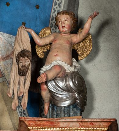 Zdjęcie nr 54: Ołtarz architektoniczny, trójosiowy, z wydzieloną częścią cokołową z bramkami bocznymi, jednokondygnacyjny, ze zwieńczeniem. Mensa drewniana z portatylem z marmuru dębnickiego, umieszczona na drewnianej, prostopadłościennej skrzyni.  Antepedium w kształcie leżącego prostokąta, ujęte profilowaną ramą dekorowaną liśćmi akantu i perełkowaniem. W polu płaskorzeźbione przedstawienie baranka leżącego na krzyżu, na obłoku, ujęte parą liści akantu oraz wicią roślinną z kwiatami i kiściami winogron. 
Na mensie tabernakulum z Tronem Łaski w formie prostopadłościanu na cokole, o wypukłej ściance frontowej, ujęte spływami wolutowymi podtrzymującymi niepełne belkowanie, wyłamane po środku łukiem półkolistym. Na froncie obrotowa nisza ujęta obramieniem w kształcie stojącego prostokąta zamkniętego łukiem nadwieszonym. W niszy ryte przedstawienie kielicha z Eucharystią w glorii, na obłoku, całość w rocaillowej ramie. Powyżej tron wystawienia z cokołem dekorowanym rocaille’em i parą ornamentalnych świeczników; ujęty parą kolumn dźwigających imposty. Podpory dżwigają rocaillowe kabłąki tworzące baldachim, na którego szczycie figurka baranka eucharystycznego leżącego na księdze. Ścianka w formie zbliżonej do stojącego prostokąta ujęta rocaille. Tabernakulum i tron ujęte okazałymi spływami wolutowymi z rocaillowymi uszami oraz na zakończeniach u dołu dwiema rzeźbami klęczących, adorujących aniołów.
Osie nastawy wydzielone w osiach skrajnych parą kolumn o skręconych trzonach i korynckich kapitelach umieszczonych na tle pilastrów, w osiach wewnętrznych parą pilastrów o trzonach w formie wolut z puttami z puttami, podtrzymywaną przez kariatydy w formie okazałych figur uskrzydlonych aniołów. Podpory wspierają pełne belkowanie z profilowanym gzymsem, występujące nad nimi, przerwane nad polem środkowym. W polu środkowym nisza ze sklepieniem kolebkowym wspartym na dwóch filarach i pilastrach. W głębi niszy obraz Św. Bartłomiej w profilowanej ramie w kształcie stojącego prostokąta zamkniętego łukiem odcinkowym. Na podniebiu niszy obraz Męczeństwo św. Bartłomieja w kształcie leżącego prostokąta ujętego niesymetrycznym obramieniem z motywem rocaille’ów. Nisza flankowana z figurami św. Stefana i św. Emeryka umieszczonymi na konsolach, na tle pilastrów. Pola retabulum w osiach skrajnych wklęsłe, między podporami prześwity z figurami św. Piotra i św. Pawła. W partii wysokiego cokołu bramki ujęte od zewnątrz wklęsłymi filarami podtrzymującymi belkowanie, wejścia z drzwiczkami w kształcie stojącego prostokąta zamkniętego łukiem półkolistym z obrazami przedstawiającymi Mojżesza i Aarona. Zwieńczenie w formie aedikuli ujętej pilastrami wspierającymi przerwane belkowanie oraz fantazyjnymi spływami wolutowymi, spływającymi na wewnętrzne podpory, przyjmując formę przerwanego przyczółka, na którym dwa putta i dwie figury siedzących aniołów. W osiach zewnętrznych podpór dwa putta siedzące kanelowanych postumentach i obłokach, prawe przytrzymuje skórę (atrybut św. Bartłomieja). W polu zwieńczenia obraz Św. Anna Samotrzeć w kształcie wydłużonego ośmioboku, w ornamentalnej ramie. Całość zwieńczona rzeźbioną półpostacią Boga Ojca pośród obłoków ukazanego w glorii promienistej. Drzwi do bramek flankowane liściastymi festonami, powyżej tarcze ujęte liśćmi laurowymi, zwieńczone koroną z klejnotem; lewa z klejnotem w postaci łabędzia z napisem: SOLI/ DEO/GLORIA, prawa z postacią ludzką z napisem: SOLI DEO HONOR. Woluty i fryz dekorowane motywami rocaille’ów oraz uskrzydlonymi główkami anielskimi. Osie boczne wypełnione ażurowymi rocaille’ami z gałązkami różanymi oraz ornamentem małżowinowo-chrząstkowym, belkowanie z podwieszonym lambrekinem z chwostami. Skręcone trzony kolumn zdobione wicią z winnej latorośli. Archiwolta nad polem środkowym dekorowana rocaille’em, rocaille’owym kartuszem i lambrekinem z chwostami. Woluty zwieńczenia, pilastry i naroża pola obrazowego dekorowane motywami rocaille’ów. 
Nastawa marmoryzowana w odcieniu jasnoszarym, profile marmoryzowane w kolorze jasnoróżowym, ornamenty i obramienia złocone.