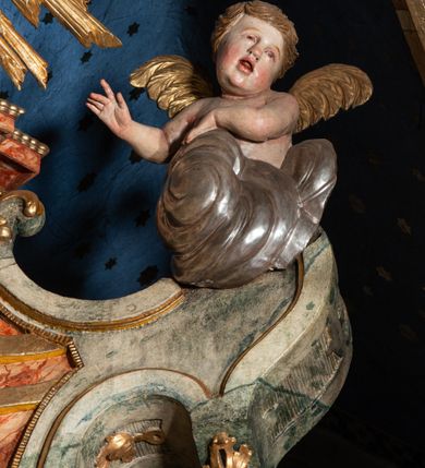 Zdjęcie nr 3: Ołtarz architektoniczny, trójosiowy, z wydzieloną częścią cokołową z bramkami bocznymi, jednokondygnacyjny, ze zwieńczeniem. Mensa drewniana z portatylem z marmuru dębnickiego, umieszczona na drewnianej, prostopadłościennej skrzyni.  Antepedium w kształcie leżącego prostokąta, ujęte profilowaną ramą dekorowaną liśćmi akantu i perełkowaniem. W polu płaskorzeźbione przedstawienie baranka leżącego na krzyżu, na obłoku, ujęte parą liści akantu oraz wicią roślinną z kwiatami i kiściami winogron. 
Na mensie tabernakulum z Tronem Łaski w formie prostopadłościanu na cokole, o wypukłej ściance frontowej, ujęte spływami wolutowymi podtrzymującymi niepełne belkowanie, wyłamane po środku łukiem półkolistym. Na froncie obrotowa nisza ujęta obramieniem w kształcie stojącego prostokąta zamkniętego łukiem nadwieszonym. W niszy ryte przedstawienie kielicha z Eucharystią w glorii, na obłoku, całość w rocaillowej ramie. Powyżej tron wystawienia z cokołem dekorowanym rocaille’em i parą ornamentalnych świeczników; ujęty parą kolumn dźwigających imposty. Podpory dżwigają rocaillowe kabłąki tworzące baldachim, na którego szczycie figurka baranka eucharystycznego leżącego na księdze. Ścianka w formie zbliżonej do stojącego prostokąta ujęta rocaille. Tabernakulum i tron ujęte okazałymi spływami wolutowymi z rocaillowymi uszami oraz na zakończeniach u dołu dwiema rzeźbami klęczących, adorujących aniołów.
Osie nastawy wydzielone w osiach skrajnych parą kolumn o skręconych trzonach i korynckich kapitelach umieszczonych na tle pilastrów, w osiach wewnętrznych parą pilastrów o trzonach w formie wolut z puttami z puttami, podtrzymywaną przez kariatydy w formie okazałych figur uskrzydlonych aniołów. Podpory wspierają pełne belkowanie z profilowanym gzymsem, występujące nad nimi, przerwane nad polem środkowym. W polu środkowym nisza ze sklepieniem kolebkowym wspartym na dwóch filarach i pilastrach. W głębi niszy obraz Św. Bartłomiej w profilowanej ramie w kształcie stojącego prostokąta zamkniętego łukiem odcinkowym. Na podniebiu niszy obraz Męczeństwo św. Bartłomieja w kształcie leżącego prostokąta ujętego niesymetrycznym obramieniem z motywem rocaille’ów. Nisza flankowana z figurami św. Stefana i św. Emeryka umieszczonymi na konsolach, na tle pilastrów. Pola retabulum w osiach skrajnych wklęsłe, między podporami prześwity z figurami św. Piotra i św. Pawła. W partii wysokiego cokołu bramki ujęte od zewnątrz wklęsłymi filarami podtrzymującymi belkowanie, wejścia z drzwiczkami w kształcie stojącego prostokąta zamkniętego łukiem półkolistym z obrazami przedstawiającymi Mojżesza i Aarona. Zwieńczenie w formie aedikuli ujętej pilastrami wspierającymi przerwane belkowanie oraz fantazyjnymi spływami wolutowymi, spływającymi na wewnętrzne podpory, przyjmując formę przerwanego przyczółka, na którym dwa putta i dwie figury siedzących aniołów. W osiach zewnętrznych podpór dwa putta siedzące kanelowanych postumentach i obłokach, prawe przytrzymuje skórę (atrybut św. Bartłomieja). W polu zwieńczenia obraz Św. Anna Samotrzeć w kształcie wydłużonego ośmioboku, w ornamentalnej ramie. Całość zwieńczona rzeźbioną półpostacią Boga Ojca pośród obłoków ukazanego w glorii promienistej. Drzwi do bramek flankowane liściastymi festonami, powyżej tarcze ujęte liśćmi laurowymi, zwieńczone koroną z klejnotem; lewa z klejnotem w postaci łabędzia z napisem: SOLI/ DEO/GLORIA, prawa z postacią ludzką z napisem: SOLI DEO HONOR. Woluty i fryz dekorowane motywami rocaille’ów oraz uskrzydlonymi główkami anielskimi. Osie boczne wypełnione ażurowymi rocaille’ami z gałązkami różanymi oraz ornamentem małżowinowo-chrząstkowym, belkowanie z podwieszonym lambrekinem z chwostami. Skręcone trzony kolumn zdobione wicią z winnej latorośli. Archiwolta nad polem środkowym dekorowana rocaille’em, rocaille’owym kartuszem i lambrekinem z chwostami. Woluty zwieńczenia, pilastry i naroża pola obrazowego dekorowane motywami rocaille’ów. 
Nastawa marmoryzowana w odcieniu jasnoszarym, profile marmoryzowane w kolorze jasnoróżowym, ornamenty i obramienia złocone.