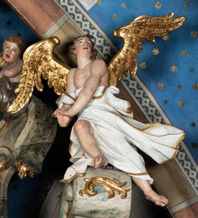 Zdjęcie nr 37: Ołtarz architektoniczny, trójosiowy, z wydzieloną częścią cokołową z bramkami bocznymi, jednokondygnacyjny, ze zwieńczeniem. Mensa drewniana z portatylem z marmuru dębnickiego, umieszczona na drewnianej, prostopadłościennej skrzyni.  Antepedium w kształcie leżącego prostokąta, ujęte profilowaną ramą dekorowaną liśćmi akantu i perełkowaniem. W polu płaskorzeźbione przedstawienie baranka leżącego na krzyżu, na obłoku, ujęte parą liści akantu oraz wicią roślinną z kwiatami i kiściami winogron. 
Na mensie tabernakulum z Tronem Łaski w formie prostopadłościanu na cokole, o wypukłej ściance frontowej, ujęte spływami wolutowymi podtrzymującymi niepełne belkowanie, wyłamane po środku łukiem półkolistym. Na froncie obrotowa nisza ujęta obramieniem w kształcie stojącego prostokąta zamkniętego łukiem nadwieszonym. W niszy ryte przedstawienie kielicha z Eucharystią w glorii, na obłoku, całość w rocaillowej ramie. Powyżej tron wystawienia z cokołem dekorowanym rocaille’em i parą ornamentalnych świeczników; ujęty parą kolumn dźwigających imposty. Podpory dżwigają rocaillowe kabłąki tworzące baldachim, na którego szczycie figurka baranka eucharystycznego leżącego na księdze. Ścianka w formie zbliżonej do stojącego prostokąta ujęta rocaille. Tabernakulum i tron ujęte okazałymi spływami wolutowymi z rocaillowymi uszami oraz na zakończeniach u dołu dwiema rzeźbami klęczących, adorujących aniołów.
Osie nastawy wydzielone w osiach skrajnych parą kolumn o skręconych trzonach i korynckich kapitelach umieszczonych na tle pilastrów, w osiach wewnętrznych parą pilastrów o trzonach w formie wolut z puttami z puttami, podtrzymywaną przez kariatydy w formie okazałych figur uskrzydlonych aniołów. Podpory wspierają pełne belkowanie z profilowanym gzymsem, występujące nad nimi, przerwane nad polem środkowym. W polu środkowym nisza ze sklepieniem kolebkowym wspartym na dwóch filarach i pilastrach. W głębi niszy obraz Św. Bartłomiej w profilowanej ramie w kształcie stojącego prostokąta zamkniętego łukiem odcinkowym. Na podniebiu niszy obraz Męczeństwo św. Bartłomieja w kształcie leżącego prostokąta ujętego niesymetrycznym obramieniem z motywem rocaille’ów. Nisza flankowana z figurami św. Stefana i św. Emeryka umieszczonymi na konsolach, na tle pilastrów. Pola retabulum w osiach skrajnych wklęsłe, między podporami prześwity z figurami św. Piotra i św. Pawła. W partii wysokiego cokołu bramki ujęte od zewnątrz wklęsłymi filarami podtrzymującymi belkowanie, wejścia z drzwiczkami w kształcie stojącego prostokąta zamkniętego łukiem półkolistym z obrazami przedstawiającymi Mojżesza i Aarona. Zwieńczenie w formie aedikuli ujętej pilastrami wspierającymi przerwane belkowanie oraz fantazyjnymi spływami wolutowymi, spływającymi na wewnętrzne podpory, przyjmując formę przerwanego przyczółka, na którym dwa putta i dwie figury siedzących aniołów. W osiach zewnętrznych podpór dwa putta siedzące kanelowanych postumentach i obłokach, prawe przytrzymuje skórę (atrybut św. Bartłomieja). W polu zwieńczenia obraz Św. Anna Samotrzeć w kształcie wydłużonego ośmioboku, w ornamentalnej ramie. Całość zwieńczona rzeźbioną półpostacią Boga Ojca pośród obłoków ukazanego w glorii promienistej. Drzwi do bramek flankowane liściastymi festonami, powyżej tarcze ujęte liśćmi laurowymi, zwieńczone koroną z klejnotem; lewa z klejnotem w postaci łabędzia z napisem: SOLI/ DEO/GLORIA, prawa z postacią ludzką z napisem: SOLI DEO HONOR. Woluty i fryz dekorowane motywami rocaille’ów oraz uskrzydlonymi główkami anielskimi. Osie boczne wypełnione ażurowymi rocaille’ami z gałązkami różanymi oraz ornamentem małżowinowo-chrząstkowym, belkowanie z podwieszonym lambrekinem z chwostami. Skręcone trzony kolumn zdobione wicią z winnej latorośli. Archiwolta nad polem środkowym dekorowana rocaille’em, rocaille’owym kartuszem i lambrekinem z chwostami. Woluty zwieńczenia, pilastry i naroża pola obrazowego dekorowane motywami rocaille’ów. 
Nastawa marmoryzowana w odcieniu jasnoszarym, profile marmoryzowane w kolorze jasnoróżowym, ornamenty i obramienia złocone.