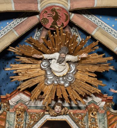 Zdjęcie nr 10: Ołtarz architektoniczny, trójosiowy, z wydzieloną częścią cokołową z bramkami bocznymi, jednokondygnacyjny, ze zwieńczeniem. Mensa drewniana z portatylem z marmuru dębnickiego, umieszczona na drewnianej, prostopadłościennej skrzyni.  Antepedium w kształcie leżącego prostokąta, ujęte profilowaną ramą dekorowaną liśćmi akantu i perełkowaniem. W polu płaskorzeźbione przedstawienie baranka leżącego na krzyżu, na obłoku, ujęte parą liści akantu oraz wicią roślinną z kwiatami i kiściami winogron. 
Na mensie tabernakulum z Tronem Łaski w formie prostopadłościanu na cokole, o wypukłej ściance frontowej, ujęte spływami wolutowymi podtrzymującymi niepełne belkowanie, wyłamane po środku łukiem półkolistym. Na froncie obrotowa nisza ujęta obramieniem w kształcie stojącego prostokąta zamkniętego łukiem nadwieszonym. W niszy ryte przedstawienie kielicha z Eucharystią w glorii, na obłoku, całość w rocaillowej ramie. Powyżej tron wystawienia z cokołem dekorowanym rocaille’em i parą ornamentalnych świeczników; ujęty parą kolumn dźwigających imposty. Podpory dżwigają rocaillowe kabłąki tworzące baldachim, na którego szczycie figurka baranka eucharystycznego leżącego na księdze. Ścianka w formie zbliżonej do stojącego prostokąta ujęta rocaille. Tabernakulum i tron ujęte okazałymi spływami wolutowymi z rocaillowymi uszami oraz na zakończeniach u dołu dwiema rzeźbami klęczących, adorujących aniołów.
Osie nastawy wydzielone w osiach skrajnych parą kolumn o skręconych trzonach i korynckich kapitelach umieszczonych na tle pilastrów, w osiach wewnętrznych parą pilastrów o trzonach w formie wolut z puttami z puttami, podtrzymywaną przez kariatydy w formie okazałych figur uskrzydlonych aniołów. Podpory wspierają pełne belkowanie z profilowanym gzymsem, występujące nad nimi, przerwane nad polem środkowym. W polu środkowym nisza ze sklepieniem kolebkowym wspartym na dwóch filarach i pilastrach. W głębi niszy obraz Św. Bartłomiej w profilowanej ramie w kształcie stojącego prostokąta zamkniętego łukiem odcinkowym. Na podniebiu niszy obraz Męczeństwo św. Bartłomieja w kształcie leżącego prostokąta ujętego niesymetrycznym obramieniem z motywem rocaille’ów. Nisza flankowana z figurami św. Stefana i św. Emeryka umieszczonymi na konsolach, na tle pilastrów. Pola retabulum w osiach skrajnych wklęsłe, między podporami prześwity z figurami św. Piotra i św. Pawła. W partii wysokiego cokołu bramki ujęte od zewnątrz wklęsłymi filarami podtrzymującymi belkowanie, wejścia z drzwiczkami w kształcie stojącego prostokąta zamkniętego łukiem półkolistym z obrazami przedstawiającymi Mojżesza i Aarona. Zwieńczenie w formie aedikuli ujętej pilastrami wspierającymi przerwane belkowanie oraz fantazyjnymi spływami wolutowymi, spływającymi na wewnętrzne podpory, przyjmując formę przerwanego przyczółka, na którym dwa putta i dwie figury siedzących aniołów. W osiach zewnętrznych podpór dwa putta siedzące kanelowanych postumentach i obłokach, prawe przytrzymuje skórę (atrybut św. Bartłomieja). W polu zwieńczenia obraz Św. Anna Samotrzeć w kształcie wydłużonego ośmioboku, w ornamentalnej ramie. Całość zwieńczona rzeźbioną półpostacią Boga Ojca pośród obłoków ukazanego w glorii promienistej. Drzwi do bramek flankowane liściastymi festonami, powyżej tarcze ujęte liśćmi laurowymi, zwieńczone koroną z klejnotem; lewa z klejnotem w postaci łabędzia z napisem: SOLI/ DEO/GLORIA, prawa z postacią ludzką z napisem: SOLI DEO HONOR. Woluty i fryz dekorowane motywami rocaille’ów oraz uskrzydlonymi główkami anielskimi. Osie boczne wypełnione ażurowymi rocaille’ami z gałązkami różanymi oraz ornamentem małżowinowo-chrząstkowym, belkowanie z podwieszonym lambrekinem z chwostami. Skręcone trzony kolumn zdobione wicią z winnej latorośli. Archiwolta nad polem środkowym dekorowana rocaille’em, rocaille’owym kartuszem i lambrekinem z chwostami. Woluty zwieńczenia, pilastry i naroża pola obrazowego dekorowane motywami rocaille’ów. 
Nastawa marmoryzowana w odcieniu jasnoszarym, profile marmoryzowane w kolorze jasnoróżowym, ornamenty i obramienia złocone.