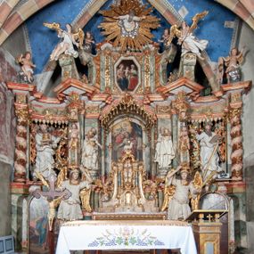 Zdjęcie nr 1: Ołtarz architektoniczny, trójosiowy, z wydzieloną częścią cokołową z bramkami bocznymi, jednokondygnacyjny, ze zwieńczeniem. Mensa drewniana z portatylem z marmuru dębnickiego, umieszczona na drewnianej, prostopadłościennej skrzyni.  Antepedium w kształcie leżącego prostokąta, ujęte profilowaną ramą dekorowaną liśćmi akantu i perełkowaniem. W polu płaskorzeźbione przedstawienie baranka leżącego na krzyżu, na obłoku, ujęte parą liści akantu oraz wicią roślinną z kwiatami i kiściami winogron. 
Na mensie tabernakulum z Tronem Łaski w formie prostopadłościanu na cokole, o wypukłej ściance frontowej, ujęte spływami wolutowymi podtrzymującymi niepełne belkowanie, wyłamane po środku łukiem półkolistym. Na froncie obrotowa nisza ujęta obramieniem w kształcie stojącego prostokąta zamkniętego łukiem nadwieszonym. W niszy ryte przedstawienie kielicha z Eucharystią w glorii, na obłoku, całość w rocaillowej ramie. Powyżej tron wystawienia z cokołem dekorowanym rocaille’em i parą ornamentalnych świeczników; ujęty parą kolumn dźwigających imposty. Podpory dżwigają rocaillowe kabłąki tworzące baldachim, na którego szczycie figurka baranka eucharystycznego leżącego na księdze. Ścianka w formie zbliżonej do stojącego prostokąta ujęta rocaille. Tabernakulum i tron ujęte okazałymi spływami wolutowymi z rocaillowymi uszami oraz na zakończeniach u dołu dwiema rzeźbami klęczących, adorujących aniołów.
Osie nastawy wydzielone w osiach skrajnych parą kolumn o skręconych trzonach i korynckich kapitelach umieszczonych na tle pilastrów, w osiach wewnętrznych parą pilastrów o trzonach w formie wolut z puttami z puttami, podtrzymywaną przez kariatydy w formie okazałych figur uskrzydlonych aniołów. Podpory wspierają pełne belkowanie z profilowanym gzymsem, występujące nad nimi, przerwane nad polem środkowym. W polu środkowym nisza ze sklepieniem kolebkowym wspartym na dwóch filarach i pilastrach. W głębi niszy obraz Św. Bartłomiej w profilowanej ramie w kształcie stojącego prostokąta zamkniętego łukiem odcinkowym. Na podniebiu niszy obraz Męczeństwo św. Bartłomieja w kształcie leżącego prostokąta ujętego niesymetrycznym obramieniem z motywem rocaille’ów. Nisza flankowana z figurami św. Stefana i św. Emeryka umieszczonymi na konsolach, na tle pilastrów. Pola retabulum w osiach skrajnych wklęsłe, między podporami prześwity z figurami św. Piotra i św. Pawła. W partii wysokiego cokołu bramki ujęte od zewnątrz wklęsłymi filarami podtrzymującymi belkowanie, wejścia z drzwiczkami w kształcie stojącego prostokąta zamkniętego łukiem półkolistym z obrazami przedstawiającymi Mojżesza i Aarona. Zwieńczenie w formie aedikuli ujętej pilastrami wspierającymi przerwane belkowanie oraz fantazyjnymi spływami wolutowymi, spływającymi na wewnętrzne podpory, przyjmując formę przerwanego przyczółka, na którym dwa putta i dwie figury siedzących aniołów. W osiach zewnętrznych podpór dwa putta siedzące kanelowanych postumentach i obłokach, prawe przytrzymuje skórę (atrybut św. Bartłomieja). W polu zwieńczenia obraz Św. Anna Samotrzeć w kształcie wydłużonego ośmioboku, w ornamentalnej ramie. Całość zwieńczona rzeźbioną półpostacią Boga Ojca pośród obłoków ukazanego w glorii promienistej. Drzwi do bramek flankowane liściastymi festonami, powyżej tarcze ujęte liśćmi laurowymi, zwieńczone koroną z klejnotem; lewa z klejnotem w postaci łabędzia z napisem: SOLI/ DEO/GLORIA, prawa z postacią ludzką z napisem: SOLI DEO HONOR. Woluty i fryz dekorowane motywami rocaille’ów oraz uskrzydlonymi główkami anielskimi. Osie boczne wypełnione ażurowymi rocaille’ami z gałązkami różanymi oraz ornamentem małżowinowo-chrząstkowym, belkowanie z podwieszonym lambrekinem z chwostami. Skręcone trzony kolumn zdobione wicią z winnej latorośli. Archiwolta nad polem środkowym dekorowana rocaille’em, rocaille’owym kartuszem i lambrekinem z chwostami. Woluty zwieńczenia, pilastry i naroża pola obrazowego dekorowane motywami rocaille’ów. 
Nastawa marmoryzowana w odcieniu jasnoszarym, profile marmoryzowane w kolorze jasnoróżowym, ornamenty i obramienia złocone.