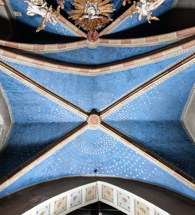 Zdjęcie nr 9: Ołtarz architektoniczny, trójosiowy, z wydzieloną częścią cokołową z bramkami bocznymi, jednokondygnacyjny, ze zwieńczeniem. Mensa drewniana z portatylem z marmuru dębnickiego, umieszczona na drewnianej, prostopadłościennej skrzyni.  Antepedium w kształcie leżącego prostokąta, ujęte profilowaną ramą dekorowaną liśćmi akantu i perełkowaniem. W polu płaskorzeźbione przedstawienie baranka leżącego na krzyżu, na obłoku, ujęte parą liści akantu oraz wicią roślinną z kwiatami i kiściami winogron. 
Na mensie tabernakulum z Tronem Łaski w formie prostopadłościanu na cokole, o wypukłej ściance frontowej, ujęte spływami wolutowymi podtrzymującymi niepełne belkowanie, wyłamane po środku łukiem półkolistym. Na froncie obrotowa nisza ujęta obramieniem w kształcie stojącego prostokąta zamkniętego łukiem nadwieszonym. W niszy ryte przedstawienie kielicha z Eucharystią w glorii, na obłoku, całość w rocaillowej ramie. Powyżej tron wystawienia z cokołem dekorowanym rocaille’em i parą ornamentalnych świeczników; ujęty parą kolumn dźwigających imposty. Podpory dżwigają rocaillowe kabłąki tworzące baldachim, na którego szczycie figurka baranka eucharystycznego leżącego na księdze. Ścianka w formie zbliżonej do stojącego prostokąta ujęta rocaille. Tabernakulum i tron ujęte okazałymi spływami wolutowymi z rocaillowymi uszami oraz na zakończeniach u dołu dwiema rzeźbami klęczących, adorujących aniołów.
Osie nastawy wydzielone w osiach skrajnych parą kolumn o skręconych trzonach i korynckich kapitelach umieszczonych na tle pilastrów, w osiach wewnętrznych parą pilastrów o trzonach w formie wolut z puttami z puttami, podtrzymywaną przez kariatydy w formie okazałych figur uskrzydlonych aniołów. Podpory wspierają pełne belkowanie z profilowanym gzymsem, występujące nad nimi, przerwane nad polem środkowym. W polu środkowym nisza ze sklepieniem kolebkowym wspartym na dwóch filarach i pilastrach. W głębi niszy obraz Św. Bartłomiej w profilowanej ramie w kształcie stojącego prostokąta zamkniętego łukiem odcinkowym. Na podniebiu niszy obraz Męczeństwo św. Bartłomieja w kształcie leżącego prostokąta ujętego niesymetrycznym obramieniem z motywem rocaille’ów. Nisza flankowana z figurami św. Stefana i św. Emeryka umieszczonymi na konsolach, na tle pilastrów. Pola retabulum w osiach skrajnych wklęsłe, między podporami prześwity z figurami św. Piotra i św. Pawła. W partii wysokiego cokołu bramki ujęte od zewnątrz wklęsłymi filarami podtrzymującymi belkowanie, wejścia z drzwiczkami w kształcie stojącego prostokąta zamkniętego łukiem półkolistym z obrazami przedstawiającymi Mojżesza i Aarona. Zwieńczenie w formie aedikuli ujętej pilastrami wspierającymi przerwane belkowanie oraz fantazyjnymi spływami wolutowymi, spływającymi na wewnętrzne podpory, przyjmując formę przerwanego przyczółka, na którym dwa putta i dwie figury siedzących aniołów. W osiach zewnętrznych podpór dwa putta siedzące kanelowanych postumentach i obłokach, prawe przytrzymuje skórę (atrybut św. Bartłomieja). W polu zwieńczenia obraz Św. Anna Samotrzeć w kształcie wydłużonego ośmioboku, w ornamentalnej ramie. Całość zwieńczona rzeźbioną półpostacią Boga Ojca pośród obłoków ukazanego w glorii promienistej. Drzwi do bramek flankowane liściastymi festonami, powyżej tarcze ujęte liśćmi laurowymi, zwieńczone koroną z klejnotem; lewa z klejnotem w postaci łabędzia z napisem: SOLI/ DEO/GLORIA, prawa z postacią ludzką z napisem: SOLI DEO HONOR. Woluty i fryz dekorowane motywami rocaille’ów oraz uskrzydlonymi główkami anielskimi. Osie boczne wypełnione ażurowymi rocaille’ami z gałązkami różanymi oraz ornamentem małżowinowo-chrząstkowym, belkowanie z podwieszonym lambrekinem z chwostami. Skręcone trzony kolumn zdobione wicią z winnej latorośli. Archiwolta nad polem środkowym dekorowana rocaille’em, rocaille’owym kartuszem i lambrekinem z chwostami. Woluty zwieńczenia, pilastry i naroża pola obrazowego dekorowane motywami rocaille’ów. 
Nastawa marmoryzowana w odcieniu jasnoszarym, profile marmoryzowane w kolorze jasnoróżowym, ornamenty i obramienia złocone.