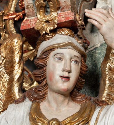 Zdjęcie nr 46: Ołtarz architektoniczny, trójosiowy, z wydzieloną częścią cokołową z bramkami bocznymi, jednokondygnacyjny, ze zwieńczeniem. Mensa drewniana z portatylem z marmuru dębnickiego, umieszczona na drewnianej, prostopadłościennej skrzyni.  Antepedium w kształcie leżącego prostokąta, ujęte profilowaną ramą dekorowaną liśćmi akantu i perełkowaniem. W polu płaskorzeźbione przedstawienie baranka leżącego na krzyżu, na obłoku, ujęte parą liści akantu oraz wicią roślinną z kwiatami i kiściami winogron. 
Na mensie tabernakulum z Tronem Łaski w formie prostopadłościanu na cokole, o wypukłej ściance frontowej, ujęte spływami wolutowymi podtrzymującymi niepełne belkowanie, wyłamane po środku łukiem półkolistym. Na froncie obrotowa nisza ujęta obramieniem w kształcie stojącego prostokąta zamkniętego łukiem nadwieszonym. W niszy ryte przedstawienie kielicha z Eucharystią w glorii, na obłoku, całość w rocaillowej ramie. Powyżej tron wystawienia z cokołem dekorowanym rocaille’em i parą ornamentalnych świeczników; ujęty parą kolumn dźwigających imposty. Podpory dżwigają rocaillowe kabłąki tworzące baldachim, na którego szczycie figurka baranka eucharystycznego leżącego na księdze. Ścianka w formie zbliżonej do stojącego prostokąta ujęta rocaille. Tabernakulum i tron ujęte okazałymi spływami wolutowymi z rocaillowymi uszami oraz na zakończeniach u dołu dwiema rzeźbami klęczących, adorujących aniołów.
Osie nastawy wydzielone w osiach skrajnych parą kolumn o skręconych trzonach i korynckich kapitelach umieszczonych na tle pilastrów, w osiach wewnętrznych parą pilastrów o trzonach w formie wolut z puttami z puttami, podtrzymywaną przez kariatydy w formie okazałych figur uskrzydlonych aniołów. Podpory wspierają pełne belkowanie z profilowanym gzymsem, występujące nad nimi, przerwane nad polem środkowym. W polu środkowym nisza ze sklepieniem kolebkowym wspartym na dwóch filarach i pilastrach. W głębi niszy obraz Św. Bartłomiej w profilowanej ramie w kształcie stojącego prostokąta zamkniętego łukiem odcinkowym. Na podniebiu niszy obraz Męczeństwo św. Bartłomieja w kształcie leżącego prostokąta ujętego niesymetrycznym obramieniem z motywem rocaille’ów. Nisza flankowana z figurami św. Stefana i św. Emeryka umieszczonymi na konsolach, na tle pilastrów. Pola retabulum w osiach skrajnych wklęsłe, między podporami prześwity z figurami św. Piotra i św. Pawła. W partii wysokiego cokołu bramki ujęte od zewnątrz wklęsłymi filarami podtrzymującymi belkowanie, wejścia z drzwiczkami w kształcie stojącego prostokąta zamkniętego łukiem półkolistym z obrazami przedstawiającymi Mojżesza i Aarona. Zwieńczenie w formie aedikuli ujętej pilastrami wspierającymi przerwane belkowanie oraz fantazyjnymi spływami wolutowymi, spływającymi na wewnętrzne podpory, przyjmując formę przerwanego przyczółka, na którym dwa putta i dwie figury siedzących aniołów. W osiach zewnętrznych podpór dwa putta siedzące kanelowanych postumentach i obłokach, prawe przytrzymuje skórę (atrybut św. Bartłomieja). W polu zwieńczenia obraz Św. Anna Samotrzeć w kształcie wydłużonego ośmioboku, w ornamentalnej ramie. Całość zwieńczona rzeźbioną półpostacią Boga Ojca pośród obłoków ukazanego w glorii promienistej. Drzwi do bramek flankowane liściastymi festonami, powyżej tarcze ujęte liśćmi laurowymi, zwieńczone koroną z klejnotem; lewa z klejnotem w postaci łabędzia z napisem: SOLI/ DEO/GLORIA, prawa z postacią ludzką z napisem: SOLI DEO HONOR. Woluty i fryz dekorowane motywami rocaille’ów oraz uskrzydlonymi główkami anielskimi. Osie boczne wypełnione ażurowymi rocaille’ami z gałązkami różanymi oraz ornamentem małżowinowo-chrząstkowym, belkowanie z podwieszonym lambrekinem z chwostami. Skręcone trzony kolumn zdobione wicią z winnej latorośli. Archiwolta nad polem środkowym dekorowana rocaille’em, rocaille’owym kartuszem i lambrekinem z chwostami. Woluty zwieńczenia, pilastry i naroża pola obrazowego dekorowane motywami rocaille’ów. 
Nastawa marmoryzowana w odcieniu jasnoszarym, profile marmoryzowane w kolorze jasnoróżowym, ornamenty i obramienia złocone.