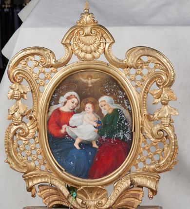 Zdjęcie nr 1: Feretron dwustronny ustawiony na prostopadłościennej podstawie zaopatrzonej w otwory na drążki do noszenia. Struktura feretronu od dołu flankowana dwiema wstęgami zdobionymi puklowaniem, spiętymi pośrodku muszlą palmetową. Boki utworzone z ażurowej kratki ujętej wolutami i ze spływającymi kampanulami. W zwieńczeniu muszla palmetowa i rocaille wraz z zatkniętym u szczytu akroterionem. W polu w owalnej, profilowanej i złoconej ramie obrazy: „Św. Anna Samotrzeć” oraz „Św. Joachim z małą Marią”. Na obrazie św. Anny Samotrzeć ukazana Matka Boska po lewej stronie, św. Anna po prawej, na kolanach Marii Dzieciątko Jezus, a nad nimi gołębica Ducha Świętego. Obie kobiety ukazane w pozycji siedzącej, zwrócone w trzech czwartych ku środkowi, rękami przytrzymujące Dzieciątko. Twarz Marii o delikatnych rysach, z prostym nosem, dużymi i brązowymi oczami oraz o wyraźnych ustach. Jej jasnobrązowe włosy są częściowo schowane pod białym welonem ze złotą lamówką. Ubrana jest w czerwoną suknię oraz niebieski płaszcz założony na lewe ramię i zasłaniający kolana. Po drugiej stronie św. Anna o twarzy cechującej się rysami starszej kobiety z włosami schowanymi całkowicie pod białym welonem ze złotą opaską wokół głowy. Ubrana jest w zieloną suknię oraz czerwony płaszcz założony na kolana. Dzieciątko Jezus zwrócone trzy czwarte w lewo, z głową skierowaną w drugą stronę, z lewą nóżką wysuniętą do przodu, w dłoniach trzymające niebieskie jabłko królewskie. Twarz o dziecięcych rysach z zarumienionymi policzkami, okolona kędzierzawymi włosami. Ubrany jest w zwiewną pieluszkę odsłaniającą ramiona, którą z jednego końca podtrzymuje Matka Boska. Nad głową Marii i św. Anny złote, koliste nimby, a wokół głowy Dzieciątka nimb krzyżowy. Tło w różnych odcieniach brązu. Po drugiej stronie feretronu obraz św. Joachima z małą Marią. W centrum kompozycji św. Joachim siedzący w fotelu i trzymający na kolanach małą Marię. Matka Boska ukazana w postawie stojącej, rękami trzymająca się św. Joachima. Twarz o rysach dziecka, z małymi ustami i nosem oraz dużymi oczami. Włosy bujne, ciemnobrązowe, upięte do tyłu, wokół głowy świetlisty nimb. Ubrana jest w białą suknię oraz ciemnoniebieski płaszcz założony na lewe ramię. Święty Joachim widoczny z prawego profilu, prawą ręką ujmujący Marię. Twarz podłużna, okolona siwą brodą oraz siwymi włosami. Ubrany jest w brązową suknię z długimi rękawami oraz zielony płaszcz przewieszony przez poręcz krzesła. Tło jednolite, brązowe. 


