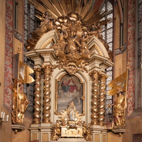 Zdjęcie nr 1: Nastawa jednoosiowa, jednokondygnacyjna ze zwieńczeniem, na wysokim dwustrefowym cokole z wyodrębnionymi czterema prostopadłościanami. Ołtarz kamienny, prostopadłościenny, z kamienną mensą. Antepedium ujęte srebrzoną opaską z napisem „kości ich niech wypuszczą pędu ze swego miejsca, aby byli wsławieni przez swoich synów”, pole podzielone na cztery części ornamentem roślinnym, każda wypełniona złoconą wicią kwiatową i czterema okrągłymi prześwitami. Na ołtarzu ustawione tabernakulum w formie Arki Przymierza. Nastawa ujęta dwiema parami pilastrów i dwiema parami kolumn o kręconych trzonach ustawionych pod kątem na zewnątrz, dźwigającymi pełne belkowanie z kostkowaniem, wyłamane na ich osi, przerwane nad polem środkowym oraz fragmenty przerwanego, półkolistego przyczółka. W polu środkowym wnęka w formie stojącego prostokąta zamkniętego łukiem półkolistym, w niej mniejszy obraz w kształcie stojącego prostokąta zamkniętego łukiem półkolistym nadwieszonym z przedstawieniem Wizji św. Franciszka, ujęty ramą dekorowaną rocaille&#039;em. Zwieńczenie w formie grupy rzeźbiarskiej Przemienienia Pańskiego na tle obłoków i w glorii promienistej. 
W partii belkowania nad polem głównym, na rzeźbionej skale podtrzymywanej przez rocaille klęczące postacie św. Piotra, św. Jana i św. Jakuba w dynamicznych pozach. Nad nimi unosi się Chrystus w otoku z obłoków i glorii, flankowany przez figury Mojżesza i Eliasza klęczące na przerwanym przyczółku, za nimi nadlatujące putta na obłokach. Po lewej stronie Piotr klęczący frontalnie z uniesionymi rękami. Obok niego klęczący św. Jan zwrócony profilem w lewo, z rękami wyciągniętymi w przód, o młodzieńczych rysach i długich, kręconych włosach. Święty Jakub po prawej stronie, w pozycji siedzącej, zwrócony w trzech czwartych w prawo z rękami wyciągniętymi w lewo. Wszyscy ubrani w przylegające do ciała tuniki oraz płaszcze przepasane w partii nóg. Nad nimi Chrystus w pozycji stojącej, frontalnie, w kontrapoście, z uniesioną głową i rękami rozłożonymi na boki, ubrany jest w tunikę oraz płaszcz przewiązany przez lewe ramię i wokół nóg. Na lewym fragmencie przyczółka klęczy Eliasz, zwrócony w trzech czwartych w lewo, pochylony, prawą ręką przytrzymuje na boku księgę, lewą wyciąga w przód. Ubrany jest w tunikę oraz rozwiany płaszcz. Na prawym fragmencie przyczółka klęczy Mojżesz, zwrócony w trzech czwartych w prawo, z pochylona głową, obiema rękami trzyma tablice przykazań. Ubrany jest w tunikę o krótkich rękawach oraz płaszcz zawinięty na lewym ramieniu i opadający na nogi. Obaj prorocy ukazani jako starcy. Nastawa flankowana dwoma wspornikami z figurami św. Wacława i św. Floriana. Struktura polichromowana w kolorze beżowym z żółtymi detalami oraz złoconymi profilami, ornamentyką i zwieńczeniem. Figury w partii ciała polichromowane naturalistycznie z brązowymi włosami i brodami oraz złoconymi szatami i atrybutami. 

