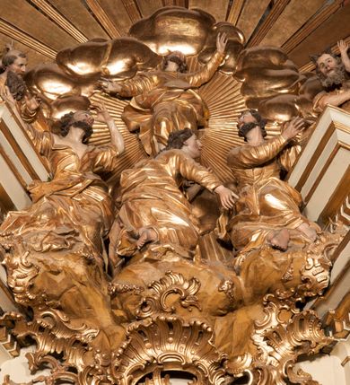 Zdjęcie nr 34: Nastawa jednoosiowa, jednokondygnacyjna ze zwieńczeniem, na wysokim dwustrefowym cokole z wyodrębnionymi czterema prostopadłościanami. Ołtarz kamienny, prostopadłościenny, z kamienną mensą. Antepedium ujęte srebrzoną opaską z napisem „kości ich niech wypuszczą pędu ze swego miejsca, aby byli wsławieni przez swoich synów”, pole podzielone na cztery części ornamentem roślinnym, każda wypełniona złoconą wicią kwiatową i czterema okrągłymi prześwitami. Na ołtarzu ustawione tabernakulum w formie Arki Przymierza. Nastawa ujęta dwiema parami pilastrów i dwiema parami kolumn o kręconych trzonach ustawionych pod kątem na zewnątrz, dźwigającymi pełne belkowanie z kostkowaniem, wyłamane na ich osi, przerwane nad polem środkowym oraz fragmenty przerwanego, półkolistego przyczółka. W polu środkowym wnęka w formie stojącego prostokąta zamkniętego łukiem półkolistym, w niej mniejszy obraz w kształcie stojącego prostokąta zamkniętego łukiem półkolistym nadwieszonym z przedstawieniem Wizji św. Franciszka, ujęty ramą dekorowaną rocaille&#039;em. Zwieńczenie w formie grupy rzeźbiarskiej Przemienienia Pańskiego na tle obłoków i w glorii promienistej. 
W partii belkowania nad polem głównym, na rzeźbionej skale podtrzymywanej przez rocaille klęczące postacie św. Piotra, św. Jana i św. Jakuba w dynamicznych pozach. Nad nimi unosi się Chrystus w otoku z obłoków i glorii, flankowany przez figury Mojżesza i Eliasza klęczące na przerwanym przyczółku, za nimi nadlatujące putta na obłokach. Po lewej stronie Piotr klęczący frontalnie z uniesionymi rękami. Obok niego klęczący św. Jan zwrócony profilem w lewo, z rękami wyciągniętymi w przód, o młodzieńczych rysach i długich, kręconych włosach. Święty Jakub po prawej stronie, w pozycji siedzącej, zwrócony w trzech czwartych w prawo z rękami wyciągniętymi w lewo. Wszyscy ubrani w przylegające do ciała tuniki oraz płaszcze przepasane w partii nóg. Nad nimi Chrystus w pozycji stojącej, frontalnie, w kontrapoście, z uniesioną głową i rękami rozłożonymi na boki, ubrany jest w tunikę oraz płaszcz przewiązany przez lewe ramię i wokół nóg. Na lewym fragmencie przyczółka klęczy Eliasz, zwrócony w trzech czwartych w lewo, pochylony, prawą ręką przytrzymuje na boku księgę, lewą wyciąga w przód. Ubrany jest w tunikę oraz rozwiany płaszcz. Na prawym fragmencie przyczółka klęczy Mojżesz, zwrócony w trzech czwartych w prawo, z pochylona głową, obiema rękami trzyma tablice przykazań. Ubrany jest w tunikę o krótkich rękawach oraz płaszcz zawinięty na lewym ramieniu i opadający na nogi. Obaj prorocy ukazani jako starcy. Nastawa flankowana dwoma wspornikami z figurami św. Wacława i św. Floriana. Struktura polichromowana w kolorze beżowym z żółtymi detalami oraz złoconymi profilami, ornamentyką i zwieńczeniem. Figury w partii ciała polichromowane naturalistycznie z brązowymi włosami i brodami oraz złoconymi szatami i atrybutami. 

