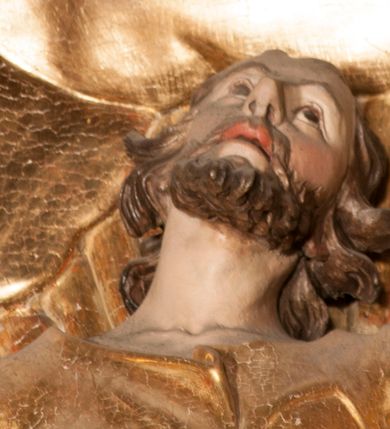 Zdjęcie nr 44: Nastawa jednoosiowa, jednokondygnacyjna ze zwieńczeniem, na wysokim dwustrefowym cokole z wyodrębnionymi czterema prostopadłościanami. Ołtarz kamienny, prostopadłościenny, z kamienną mensą. Antepedium ujęte srebrzoną opaską z napisem „kości ich niech wypuszczą pędu ze swego miejsca, aby byli wsławieni przez swoich synów”, pole podzielone na cztery części ornamentem roślinnym, każda wypełniona złoconą wicią kwiatową i czterema okrągłymi prześwitami. Na ołtarzu ustawione tabernakulum w formie Arki Przymierza. Nastawa ujęta dwiema parami pilastrów i dwiema parami kolumn o kręconych trzonach ustawionych pod kątem na zewnątrz, dźwigającymi pełne belkowanie z kostkowaniem, wyłamane na ich osi, przerwane nad polem środkowym oraz fragmenty przerwanego, półkolistego przyczółka. W polu środkowym wnęka w formie stojącego prostokąta zamkniętego łukiem półkolistym, w niej mniejszy obraz w kształcie stojącego prostokąta zamkniętego łukiem półkolistym nadwieszonym z przedstawieniem Wizji św. Franciszka, ujęty ramą dekorowaną rocaille&#039;em. Zwieńczenie w formie grupy rzeźbiarskiej Przemienienia Pańskiego na tle obłoków i w glorii promienistej. 
W partii belkowania nad polem głównym, na rzeźbionej skale podtrzymywanej przez rocaille klęczące postacie św. Piotra, św. Jana i św. Jakuba w dynamicznych pozach. Nad nimi unosi się Chrystus w otoku z obłoków i glorii, flankowany przez figury Mojżesza i Eliasza klęczące na przerwanym przyczółku, za nimi nadlatujące putta na obłokach. Po lewej stronie Piotr klęczący frontalnie z uniesionymi rękami. Obok niego klęczący św. Jan zwrócony profilem w lewo, z rękami wyciągniętymi w przód, o młodzieńczych rysach i długich, kręconych włosach. Święty Jakub po prawej stronie, w pozycji siedzącej, zwrócony w trzech czwartych w prawo z rękami wyciągniętymi w lewo. Wszyscy ubrani w przylegające do ciała tuniki oraz płaszcze przepasane w partii nóg. Nad nimi Chrystus w pozycji stojącej, frontalnie, w kontrapoście, z uniesioną głową i rękami rozłożonymi na boki, ubrany jest w tunikę oraz płaszcz przewiązany przez lewe ramię i wokół nóg. Na lewym fragmencie przyczółka klęczy Eliasz, zwrócony w trzech czwartych w lewo, pochylony, prawą ręką przytrzymuje na boku księgę, lewą wyciąga w przód. Ubrany jest w tunikę oraz rozwiany płaszcz. Na prawym fragmencie przyczółka klęczy Mojżesz, zwrócony w trzech czwartych w prawo, z pochylona głową, obiema rękami trzyma tablice przykazań. Ubrany jest w tunikę o krótkich rękawach oraz płaszcz zawinięty na lewym ramieniu i opadający na nogi. Obaj prorocy ukazani jako starcy. Nastawa flankowana dwoma wspornikami z figurami św. Wacława i św. Floriana. Struktura polichromowana w kolorze beżowym z żółtymi detalami oraz złoconymi profilami, ornamentyką i zwieńczeniem. Figury w partii ciała polichromowane naturalistycznie z brązowymi włosami i brodami oraz złoconymi szatami i atrybutami. 

