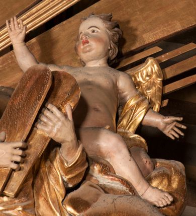 Zdjęcie nr 39: Nastawa jednoosiowa, jednokondygnacyjna ze zwieńczeniem, na wysokim dwustrefowym cokole z wyodrębnionymi czterema prostopadłościanami. Ołtarz kamienny, prostopadłościenny, z kamienną mensą. Antepedium ujęte srebrzoną opaską z napisem „kości ich niech wypuszczą pędu ze swego miejsca, aby byli wsławieni przez swoich synów”, pole podzielone na cztery części ornamentem roślinnym, każda wypełniona złoconą wicią kwiatową i czterema okrągłymi prześwitami. Na ołtarzu ustawione tabernakulum w formie Arki Przymierza. Nastawa ujęta dwiema parami pilastrów i dwiema parami kolumn o kręconych trzonach ustawionych pod kątem na zewnątrz, dźwigającymi pełne belkowanie z kostkowaniem, wyłamane na ich osi, przerwane nad polem środkowym oraz fragmenty przerwanego, półkolistego przyczółka. W polu środkowym wnęka w formie stojącego prostokąta zamkniętego łukiem półkolistym, w niej mniejszy obraz w kształcie stojącego prostokąta zamkniętego łukiem półkolistym nadwieszonym z przedstawieniem Wizji św. Franciszka, ujęty ramą dekorowaną rocaille&#039;em. Zwieńczenie w formie grupy rzeźbiarskiej Przemienienia Pańskiego na tle obłoków i w glorii promienistej. 
W partii belkowania nad polem głównym, na rzeźbionej skale podtrzymywanej przez rocaille klęczące postacie św. Piotra, św. Jana i św. Jakuba w dynamicznych pozach. Nad nimi unosi się Chrystus w otoku z obłoków i glorii, flankowany przez figury Mojżesza i Eliasza klęczące na przerwanym przyczółku, za nimi nadlatujące putta na obłokach. Po lewej stronie Piotr klęczący frontalnie z uniesionymi rękami. Obok niego klęczący św. Jan zwrócony profilem w lewo, z rękami wyciągniętymi w przód, o młodzieńczych rysach i długich, kręconych włosach. Święty Jakub po prawej stronie, w pozycji siedzącej, zwrócony w trzech czwartych w prawo z rękami wyciągniętymi w lewo. Wszyscy ubrani w przylegające do ciała tuniki oraz płaszcze przepasane w partii nóg. Nad nimi Chrystus w pozycji stojącej, frontalnie, w kontrapoście, z uniesioną głową i rękami rozłożonymi na boki, ubrany jest w tunikę oraz płaszcz przewiązany przez lewe ramię i wokół nóg. Na lewym fragmencie przyczółka klęczy Eliasz, zwrócony w trzech czwartych w lewo, pochylony, prawą ręką przytrzymuje na boku księgę, lewą wyciąga w przód. Ubrany jest w tunikę oraz rozwiany płaszcz. Na prawym fragmencie przyczółka klęczy Mojżesz, zwrócony w trzech czwartych w prawo, z pochylona głową, obiema rękami trzyma tablice przykazań. Ubrany jest w tunikę o krótkich rękawach oraz płaszcz zawinięty na lewym ramieniu i opadający na nogi. Obaj prorocy ukazani jako starcy. Nastawa flankowana dwoma wspornikami z figurami św. Wacława i św. Floriana. Struktura polichromowana w kolorze beżowym z żółtymi detalami oraz złoconymi profilami, ornamentyką i zwieńczeniem. Figury w partii ciała polichromowane naturalistycznie z brązowymi włosami i brodami oraz złoconymi szatami i atrybutami. 

