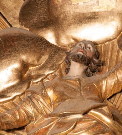 Zdjęcie nr 43: Nastawa jednoosiowa, jednokondygnacyjna ze zwieńczeniem, na wysokim dwustrefowym cokole z wyodrębnionymi czterema prostopadłościanami. Ołtarz kamienny, prostopadłościenny, z kamienną mensą. Antepedium ujęte srebrzoną opaską z napisem „kości ich niech wypuszczą pędu ze swego miejsca, aby byli wsławieni przez swoich synów”, pole podzielone na cztery części ornamentem roślinnym, każda wypełniona złoconą wicią kwiatową i czterema okrągłymi prześwitami. Na ołtarzu ustawione tabernakulum w formie Arki Przymierza. Nastawa ujęta dwiema parami pilastrów i dwiema parami kolumn o kręconych trzonach ustawionych pod kątem na zewnątrz, dźwigającymi pełne belkowanie z kostkowaniem, wyłamane na ich osi, przerwane nad polem środkowym oraz fragmenty przerwanego, półkolistego przyczółka. W polu środkowym wnęka w formie stojącego prostokąta zamkniętego łukiem półkolistym, w niej mniejszy obraz w kształcie stojącego prostokąta zamkniętego łukiem półkolistym nadwieszonym z przedstawieniem Wizji św. Franciszka, ujęty ramą dekorowaną rocaille&#039;em. Zwieńczenie w formie grupy rzeźbiarskiej Przemienienia Pańskiego na tle obłoków i w glorii promienistej. 
W partii belkowania nad polem głównym, na rzeźbionej skale podtrzymywanej przez rocaille klęczące postacie św. Piotra, św. Jana i św. Jakuba w dynamicznych pozach. Nad nimi unosi się Chrystus w otoku z obłoków i glorii, flankowany przez figury Mojżesza i Eliasza klęczące na przerwanym przyczółku, za nimi nadlatujące putta na obłokach. Po lewej stronie Piotr klęczący frontalnie z uniesionymi rękami. Obok niego klęczący św. Jan zwrócony profilem w lewo, z rękami wyciągniętymi w przód, o młodzieńczych rysach i długich, kręconych włosach. Święty Jakub po prawej stronie, w pozycji siedzącej, zwrócony w trzech czwartych w prawo z rękami wyciągniętymi w lewo. Wszyscy ubrani w przylegające do ciała tuniki oraz płaszcze przepasane w partii nóg. Nad nimi Chrystus w pozycji stojącej, frontalnie, w kontrapoście, z uniesioną głową i rękami rozłożonymi na boki, ubrany jest w tunikę oraz płaszcz przewiązany przez lewe ramię i wokół nóg. Na lewym fragmencie przyczółka klęczy Eliasz, zwrócony w trzech czwartych w lewo, pochylony, prawą ręką przytrzymuje na boku księgę, lewą wyciąga w przód. Ubrany jest w tunikę oraz rozwiany płaszcz. Na prawym fragmencie przyczółka klęczy Mojżesz, zwrócony w trzech czwartych w prawo, z pochylona głową, obiema rękami trzyma tablice przykazań. Ubrany jest w tunikę o krótkich rękawach oraz płaszcz zawinięty na lewym ramieniu i opadający na nogi. Obaj prorocy ukazani jako starcy. Nastawa flankowana dwoma wspornikami z figurami św. Wacława i św. Floriana. Struktura polichromowana w kolorze beżowym z żółtymi detalami oraz złoconymi profilami, ornamentyką i zwieńczeniem. Figury w partii ciała polichromowane naturalistycznie z brązowymi włosami i brodami oraz złoconymi szatami i atrybutami. 

