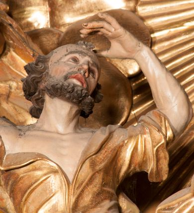 Zdjęcie nr 50: Nastawa jednoosiowa, jednokondygnacyjna ze zwieńczeniem, na wysokim dwustrefowym cokole z wyodrębnionymi czterema prostopadłościanami. Ołtarz kamienny, prostopadłościenny, z kamienną mensą. Antepedium ujęte srebrzoną opaską z napisem „kości ich niech wypuszczą pędu ze swego miejsca, aby byli wsławieni przez swoich synów”, pole podzielone na cztery części ornamentem roślinnym, każda wypełniona złoconą wicią kwiatową i czterema okrągłymi prześwitami. Na ołtarzu ustawione tabernakulum w formie Arki Przymierza. Nastawa ujęta dwiema parami pilastrów i dwiema parami kolumn o kręconych trzonach ustawionych pod kątem na zewnątrz, dźwigającymi pełne belkowanie z kostkowaniem, wyłamane na ich osi, przerwane nad polem środkowym oraz fragmenty przerwanego, półkolistego przyczółka. W polu środkowym wnęka w formie stojącego prostokąta zamkniętego łukiem półkolistym, w niej mniejszy obraz w kształcie stojącego prostokąta zamkniętego łukiem półkolistym nadwieszonym z przedstawieniem Wizji św. Franciszka, ujęty ramą dekorowaną rocaille&#039;em. Zwieńczenie w formie grupy rzeźbiarskiej Przemienienia Pańskiego na tle obłoków i w glorii promienistej. 
W partii belkowania nad polem głównym, na rzeźbionej skale podtrzymywanej przez rocaille klęczące postacie św. Piotra, św. Jana i św. Jakuba w dynamicznych pozach. Nad nimi unosi się Chrystus w otoku z obłoków i glorii, flankowany przez figury Mojżesza i Eliasza klęczące na przerwanym przyczółku, za nimi nadlatujące putta na obłokach. Po lewej stronie Piotr klęczący frontalnie z uniesionymi rękami. Obok niego klęczący św. Jan zwrócony profilem w lewo, z rękami wyciągniętymi w przód, o młodzieńczych rysach i długich, kręconych włosach. Święty Jakub po prawej stronie, w pozycji siedzącej, zwrócony w trzech czwartych w prawo z rękami wyciągniętymi w lewo. Wszyscy ubrani w przylegające do ciała tuniki oraz płaszcze przepasane w partii nóg. Nad nimi Chrystus w pozycji stojącej, frontalnie, w kontrapoście, z uniesioną głową i rękami rozłożonymi na boki, ubrany jest w tunikę oraz płaszcz przewiązany przez lewe ramię i wokół nóg. Na lewym fragmencie przyczółka klęczy Eliasz, zwrócony w trzech czwartych w lewo, pochylony, prawą ręką przytrzymuje na boku księgę, lewą wyciąga w przód. Ubrany jest w tunikę oraz rozwiany płaszcz. Na prawym fragmencie przyczółka klęczy Mojżesz, zwrócony w trzech czwartych w prawo, z pochylona głową, obiema rękami trzyma tablice przykazań. Ubrany jest w tunikę o krótkich rękawach oraz płaszcz zawinięty na lewym ramieniu i opadający na nogi. Obaj prorocy ukazani jako starcy. Nastawa flankowana dwoma wspornikami z figurami św. Wacława i św. Floriana. Struktura polichromowana w kolorze beżowym z żółtymi detalami oraz złoconymi profilami, ornamentyką i zwieńczeniem. Figury w partii ciała polichromowane naturalistycznie z brązowymi włosami i brodami oraz złoconymi szatami i atrybutami. 

