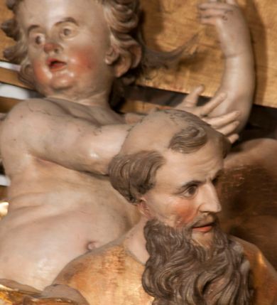 Zdjęcie nr 55: Nastawa jednoosiowa, jednokondygnacyjna ze zwieńczeniem, na wysokim dwustrefowym cokole z wyodrębnionymi czterema prostopadłościanami. Ołtarz kamienny, prostopadłościenny, z kamienną mensą. Antepedium ujęte srebrzoną opaską z napisem „kości ich niech wypuszczą pędu ze swego miejsca, aby byli wsławieni przez swoich synów”, pole podzielone na cztery części ornamentem roślinnym, każda wypełniona złoconą wicią kwiatową i czterema okrągłymi prześwitami. Na ołtarzu ustawione tabernakulum w formie Arki Przymierza. Nastawa ujęta dwiema parami pilastrów i dwiema parami kolumn o kręconych trzonach ustawionych pod kątem na zewnątrz, dźwigającymi pełne belkowanie z kostkowaniem, wyłamane na ich osi, przerwane nad polem środkowym oraz fragmenty przerwanego, półkolistego przyczółka. W polu środkowym wnęka w formie stojącego prostokąta zamkniętego łukiem półkolistym, w niej mniejszy obraz w kształcie stojącego prostokąta zamkniętego łukiem półkolistym nadwieszonym z przedstawieniem Wizji św. Franciszka, ujęty ramą dekorowaną rocaille&#039;em. Zwieńczenie w formie grupy rzeźbiarskiej Przemienienia Pańskiego na tle obłoków i w glorii promienistej. 
W partii belkowania nad polem głównym, na rzeźbionej skale podtrzymywanej przez rocaille klęczące postacie św. Piotra, św. Jana i św. Jakuba w dynamicznych pozach. Nad nimi unosi się Chrystus w otoku z obłoków i glorii, flankowany przez figury Mojżesza i Eliasza klęczące na przerwanym przyczółku, za nimi nadlatujące putta na obłokach. Po lewej stronie Piotr klęczący frontalnie z uniesionymi rękami. Obok niego klęczący św. Jan zwrócony profilem w lewo, z rękami wyciągniętymi w przód, o młodzieńczych rysach i długich, kręconych włosach. Święty Jakub po prawej stronie, w pozycji siedzącej, zwrócony w trzech czwartych w prawo z rękami wyciągniętymi w lewo. Wszyscy ubrani w przylegające do ciała tuniki oraz płaszcze przepasane w partii nóg. Nad nimi Chrystus w pozycji stojącej, frontalnie, w kontrapoście, z uniesioną głową i rękami rozłożonymi na boki, ubrany jest w tunikę oraz płaszcz przewiązany przez lewe ramię i wokół nóg. Na lewym fragmencie przyczółka klęczy Eliasz, zwrócony w trzech czwartych w lewo, pochylony, prawą ręką przytrzymuje na boku księgę, lewą wyciąga w przód. Ubrany jest w tunikę oraz rozwiany płaszcz. Na prawym fragmencie przyczółka klęczy Mojżesz, zwrócony w trzech czwartych w prawo, z pochylona głową, obiema rękami trzyma tablice przykazań. Ubrany jest w tunikę o krótkich rękawach oraz płaszcz zawinięty na lewym ramieniu i opadający na nogi. Obaj prorocy ukazani jako starcy. Nastawa flankowana dwoma wspornikami z figurami św. Wacława i św. Floriana. Struktura polichromowana w kolorze beżowym z żółtymi detalami oraz złoconymi profilami, ornamentyką i zwieńczeniem. Figury w partii ciała polichromowane naturalistycznie z brązowymi włosami i brodami oraz złoconymi szatami i atrybutami. 

