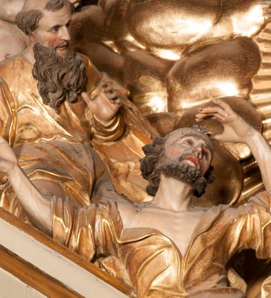 Zdjęcie nr 52: Nastawa jednoosiowa, jednokondygnacyjna ze zwieńczeniem, na wysokim dwustrefowym cokole z wyodrębnionymi czterema prostopadłościanami. Ołtarz kamienny, prostopadłościenny, z kamienną mensą. Antepedium ujęte srebrzoną opaską z napisem „kości ich niech wypuszczą pędu ze swego miejsca, aby byli wsławieni przez swoich synów”, pole podzielone na cztery części ornamentem roślinnym, każda wypełniona złoconą wicią kwiatową i czterema okrągłymi prześwitami. Na ołtarzu ustawione tabernakulum w formie Arki Przymierza. Nastawa ujęta dwiema parami pilastrów i dwiema parami kolumn o kręconych trzonach ustawionych pod kątem na zewnątrz, dźwigającymi pełne belkowanie z kostkowaniem, wyłamane na ich osi, przerwane nad polem środkowym oraz fragmenty przerwanego, półkolistego przyczółka. W polu środkowym wnęka w formie stojącego prostokąta zamkniętego łukiem półkolistym, w niej mniejszy obraz w kształcie stojącego prostokąta zamkniętego łukiem półkolistym nadwieszonym z przedstawieniem Wizji św. Franciszka, ujęty ramą dekorowaną rocaille&#039;em. Zwieńczenie w formie grupy rzeźbiarskiej Przemienienia Pańskiego na tle obłoków i w glorii promienistej. 
W partii belkowania nad polem głównym, na rzeźbionej skale podtrzymywanej przez rocaille klęczące postacie św. Piotra, św. Jana i św. Jakuba w dynamicznych pozach. Nad nimi unosi się Chrystus w otoku z obłoków i glorii, flankowany przez figury Mojżesza i Eliasza klęczące na przerwanym przyczółku, za nimi nadlatujące putta na obłokach. Po lewej stronie Piotr klęczący frontalnie z uniesionymi rękami. Obok niego klęczący św. Jan zwrócony profilem w lewo, z rękami wyciągniętymi w przód, o młodzieńczych rysach i długich, kręconych włosach. Święty Jakub po prawej stronie, w pozycji siedzącej, zwrócony w trzech czwartych w prawo z rękami wyciągniętymi w lewo. Wszyscy ubrani w przylegające do ciała tuniki oraz płaszcze przepasane w partii nóg. Nad nimi Chrystus w pozycji stojącej, frontalnie, w kontrapoście, z uniesioną głową i rękami rozłożonymi na boki, ubrany jest w tunikę oraz płaszcz przewiązany przez lewe ramię i wokół nóg. Na lewym fragmencie przyczółka klęczy Eliasz, zwrócony w trzech czwartych w lewo, pochylony, prawą ręką przytrzymuje na boku księgę, lewą wyciąga w przód. Ubrany jest w tunikę oraz rozwiany płaszcz. Na prawym fragmencie przyczółka klęczy Mojżesz, zwrócony w trzech czwartych w prawo, z pochylona głową, obiema rękami trzyma tablice przykazań. Ubrany jest w tunikę o krótkich rękawach oraz płaszcz zawinięty na lewym ramieniu i opadający na nogi. Obaj prorocy ukazani jako starcy. Nastawa flankowana dwoma wspornikami z figurami św. Wacława i św. Floriana. Struktura polichromowana w kolorze beżowym z żółtymi detalami oraz złoconymi profilami, ornamentyką i zwieńczeniem. Figury w partii ciała polichromowane naturalistycznie z brązowymi włosami i brodami oraz złoconymi szatami i atrybutami. 

