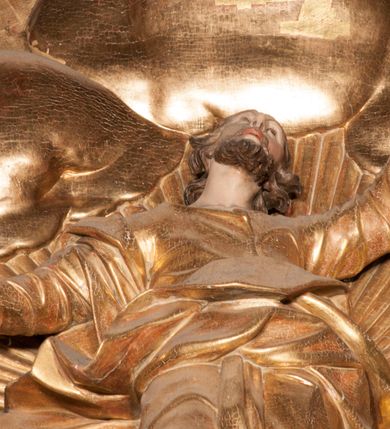 Zdjęcie nr 58: Nastawa jednoosiowa, jednokondygnacyjna ze zwieńczeniem, na wysokim dwustrefowym cokole z wyodrębnionymi czterema prostopadłościanami. Ołtarz kamienny, prostopadłościenny, z kamienną mensą. Antepedium ujęte srebrzoną opaską z napisem „kości ich niech wypuszczą pędu ze swego miejsca, aby byli wsławieni przez swoich synów”, pole podzielone na cztery części ornamentem roślinnym, każda wypełniona złoconą wicią kwiatową i czterema okrągłymi prześwitami. Na ołtarzu ustawione tabernakulum w formie Arki Przymierza. Nastawa ujęta dwiema parami pilastrów i dwiema parami kolumn o kręconych trzonach ustawionych pod kątem na zewnątrz, dźwigającymi pełne belkowanie z kostkowaniem, wyłamane na ich osi, przerwane nad polem środkowym oraz fragmenty przerwanego, półkolistego przyczółka. W polu środkowym wnęka w formie stojącego prostokąta zamkniętego łukiem półkolistym, w niej mniejszy obraz w kształcie stojącego prostokąta zamkniętego łukiem półkolistym nadwieszonym z przedstawieniem Wizji św. Franciszka, ujęty ramą dekorowaną rocaille&#039;em. Zwieńczenie w formie grupy rzeźbiarskiej Przemienienia Pańskiego na tle obłoków i w glorii promienistej. 
W partii belkowania nad polem głównym, na rzeźbionej skale podtrzymywanej przez rocaille klęczące postacie św. Piotra, św. Jana i św. Jakuba w dynamicznych pozach. Nad nimi unosi się Chrystus w otoku z obłoków i glorii, flankowany przez figury Mojżesza i Eliasza klęczące na przerwanym przyczółku, za nimi nadlatujące putta na obłokach. Po lewej stronie Piotr klęczący frontalnie z uniesionymi rękami. Obok niego klęczący św. Jan zwrócony profilem w lewo, z rękami wyciągniętymi w przód, o młodzieńczych rysach i długich, kręconych włosach. Święty Jakub po prawej stronie, w pozycji siedzącej, zwrócony w trzech czwartych w prawo z rękami wyciągniętymi w lewo. Wszyscy ubrani w przylegające do ciała tuniki oraz płaszcze przepasane w partii nóg. Nad nimi Chrystus w pozycji stojącej, frontalnie, w kontrapoście, z uniesioną głową i rękami rozłożonymi na boki, ubrany jest w tunikę oraz płaszcz przewiązany przez lewe ramię i wokół nóg. Na lewym fragmencie przyczółka klęczy Eliasz, zwrócony w trzech czwartych w lewo, pochylony, prawą ręką przytrzymuje na boku księgę, lewą wyciąga w przód. Ubrany jest w tunikę oraz rozwiany płaszcz. Na prawym fragmencie przyczółka klęczy Mojżesz, zwrócony w trzech czwartych w prawo, z pochylona głową, obiema rękami trzyma tablice przykazań. Ubrany jest w tunikę o krótkich rękawach oraz płaszcz zawinięty na lewym ramieniu i opadający na nogi. Obaj prorocy ukazani jako starcy. Nastawa flankowana dwoma wspornikami z figurami św. Wacława i św. Floriana. Struktura polichromowana w kolorze beżowym z żółtymi detalami oraz złoconymi profilami, ornamentyką i zwieńczeniem. Figury w partii ciała polichromowane naturalistycznie z brązowymi włosami i brodami oraz złoconymi szatami i atrybutami. 

