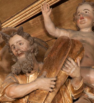 Zdjęcie nr 12: Nastawa jednoosiowa, jednokondygnacyjna ze zwieńczeniem, na wysokim dwustrefowym cokole z wyodrębnionymi czterema prostopadłościanami. Ołtarz kamienny, prostopadłościenny, z kamienną mensą. Antepedium ujęte srebrzoną opaską z napisem „kości ich niech wypuszczą pędu ze swego miejsca, aby byli wsławieni przez swoich synów”, pole podzielone na cztery części ornamentem roślinnym, każda wypełniona złoconą wicią kwiatową i czterema okrągłymi prześwitami. Na ołtarzu ustawione tabernakulum w formie Arki Przymierza. Nastawa ujęta dwiema parami pilastrów i dwiema parami kolumn o kręconych trzonach ustawionych pod kątem na zewnątrz, dźwigającymi pełne belkowanie z kostkowaniem, wyłamane na ich osi, przerwane nad polem środkowym oraz fragmenty przerwanego, półkolistego przyczółka. W polu środkowym wnęka w formie stojącego prostokąta zamkniętego łukiem półkolistym, w niej mniejszy obraz w kształcie stojącego prostokąta zamkniętego łukiem półkolistym nadwieszonym z przedstawieniem Wizji św. Franciszka, ujęty ramą dekorowaną rocaille'em. Zwieńczenie w formie grupy rzeźbiarskiej Przemienienia Pańskiego na tle obłoków i w glorii promienistej. 
W partii belkowania nad polem głównym, na rzeźbionej skale podtrzymywanej przez rocaille klęczące postacie św. Piotra, św. Jana i św. Jakuba w dynamicznych pozach. Nad nimi unosi się Chrystus w otoku z obłoków i glorii, flankowany przez figury Mojżesza i Eliasza klęczące na przerwanym przyczółku, za nimi nadlatujące putta na obłokach. Po lewej stronie Piotr klęczący frontalnie z uniesionymi rękami. Obok niego klęczący św. Jan zwrócony profilem w lewo, z rękami wyciągniętymi w przód, o młodzieńczych rysach i długich, kręconych włosach. Święty Jakub po prawej stronie, w pozycji siedzącej, zwrócony w trzech czwartych w prawo z rękami wyciągniętymi w lewo. Wszyscy ubrani w przylegające do ciała tuniki oraz płaszcze przepasane w partii nóg. Nad nimi Chrystus w pozycji stojącej, frontalnie, w kontrapoście, z uniesioną głową i rękami rozłożonymi na boki, ubrany jest w tunikę oraz płaszcz przewiązany przez lewe ramię i wokół nóg. Na lewym fragmencie przyczółka klęczy Eliasz, zwrócony w trzech czwartych w lewo, pochylony, prawą ręką przytrzymuje na boku księgę, lewą wyciąga w przód. Ubrany jest w tunikę oraz rozwiany płaszcz. Na prawym fragmencie przyczółka klęczy Mojżesz, zwrócony w trzech czwartych w prawo, z pochylona głową, obiema rękami trzyma tablice przykazań. Ubrany jest w tunikę o krótkich rękawach oraz płaszcz zawinięty na lewym ramieniu i opadający na nogi. Obaj prorocy ukazani jako starcy. Nastawa flankowana dwoma wspornikami z figurami św. Wacława i św. Floriana. Struktura polichromowana w kolorze beżowym z żółtymi detalami oraz złoconymi profilami, ornamentyką i zwieńczeniem. Figury w partii ciała polichromowane naturalistycznie z brązowymi włosami i brodami oraz złoconymi szatami i atrybutami. 

