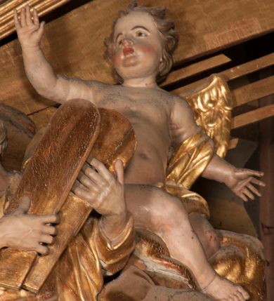 Zdjęcie nr 11: Nastawa jednoosiowa, jednokondygnacyjna ze zwieńczeniem, na wysokim dwustrefowym cokole z wyodrębnionymi czterema prostopadłościanami. Ołtarz kamienny, prostopadłościenny, z kamienną mensą. Antepedium ujęte srebrzoną opaską z napisem „kości ich niech wypuszczą pędu ze swego miejsca, aby byli wsławieni przez swoich synów”, pole podzielone na cztery części ornamentem roślinnym, każda wypełniona złoconą wicią kwiatową i czterema okrągłymi prześwitami. Na ołtarzu ustawione tabernakulum w formie Arki Przymierza. Nastawa ujęta dwiema parami pilastrów i dwiema parami kolumn o kręconych trzonach ustawionych pod kątem na zewnątrz, dźwigającymi pełne belkowanie z kostkowaniem, wyłamane na ich osi, przerwane nad polem środkowym oraz fragmenty przerwanego, półkolistego przyczółka. W polu środkowym wnęka w formie stojącego prostokąta zamkniętego łukiem półkolistym, w niej mniejszy obraz w kształcie stojącego prostokąta zamkniętego łukiem półkolistym nadwieszonym z przedstawieniem Wizji św. Franciszka, ujęty ramą dekorowaną rocaille'em. Zwieńczenie w formie grupy rzeźbiarskiej Przemienienia Pańskiego na tle obłoków i w glorii promienistej. 
W partii belkowania nad polem głównym, na rzeźbionej skale podtrzymywanej przez rocaille klęczące postacie św. Piotra, św. Jana i św. Jakuba w dynamicznych pozach. Nad nimi unosi się Chrystus w otoku z obłoków i glorii, flankowany przez figury Mojżesza i Eliasza klęczące na przerwanym przyczółku, za nimi nadlatujące putta na obłokach. Po lewej stronie Piotr klęczący frontalnie z uniesionymi rękami. Obok niego klęczący św. Jan zwrócony profilem w lewo, z rękami wyciągniętymi w przód, o młodzieńczych rysach i długich, kręconych włosach. Święty Jakub po prawej stronie, w pozycji siedzącej, zwrócony w trzech czwartych w prawo z rękami wyciągniętymi w lewo. Wszyscy ubrani w przylegające do ciała tuniki oraz płaszcze przepasane w partii nóg. Nad nimi Chrystus w pozycji stojącej, frontalnie, w kontrapoście, z uniesioną głową i rękami rozłożonymi na boki, ubrany jest w tunikę oraz płaszcz przewiązany przez lewe ramię i wokół nóg. Na lewym fragmencie przyczółka klęczy Eliasz, zwrócony w trzech czwartych w lewo, pochylony, prawą ręką przytrzymuje na boku księgę, lewą wyciąga w przód. Ubrany jest w tunikę oraz rozwiany płaszcz. Na prawym fragmencie przyczółka klęczy Mojżesz, zwrócony w trzech czwartych w prawo, z pochylona głową, obiema rękami trzyma tablice przykazań. Ubrany jest w tunikę o krótkich rękawach oraz płaszcz zawinięty na lewym ramieniu i opadający na nogi. Obaj prorocy ukazani jako starcy. Nastawa flankowana dwoma wspornikami z figurami św. Wacława i św. Floriana. Struktura polichromowana w kolorze beżowym z żółtymi detalami oraz złoconymi profilami, ornamentyką i zwieńczeniem. Figury w partii ciała polichromowane naturalistycznie z brązowymi włosami i brodami oraz złoconymi szatami i atrybutami. 

