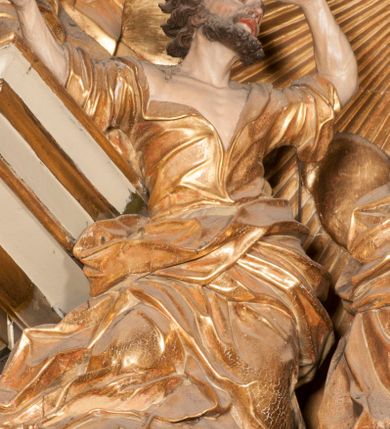 Zdjęcie nr 17: Nastawa jednoosiowa, jednokondygnacyjna ze zwieńczeniem, na wysokim dwustrefowym cokole z wyodrębnionymi czterema prostopadłościanami. Ołtarz kamienny, prostopadłościenny, z kamienną mensą. Antepedium ujęte srebrzoną opaską z napisem „kości ich niech wypuszczą pędu ze swego miejsca, aby byli wsławieni przez swoich synów”, pole podzielone na cztery części ornamentem roślinnym, każda wypełniona złoconą wicią kwiatową i czterema okrągłymi prześwitami. Na ołtarzu ustawione tabernakulum w formie Arki Przymierza. Nastawa ujęta dwiema parami pilastrów i dwiema parami kolumn o kręconych trzonach ustawionych pod kątem na zewnątrz, dźwigającymi pełne belkowanie z kostkowaniem, wyłamane na ich osi, przerwane nad polem środkowym oraz fragmenty przerwanego, półkolistego przyczółka. W polu środkowym wnęka w formie stojącego prostokąta zamkniętego łukiem półkolistym, w niej mniejszy obraz w kształcie stojącego prostokąta zamkniętego łukiem półkolistym nadwieszonym z przedstawieniem Wizji św. Franciszka, ujęty ramą dekorowaną rocaille&#039;em. Zwieńczenie w formie grupy rzeźbiarskiej Przemienienia Pańskiego na tle obłoków i w glorii promienistej. 
W partii belkowania nad polem głównym, na rzeźbionej skale podtrzymywanej przez rocaille klęczące postacie św. Piotra, św. Jana i św. Jakuba w dynamicznych pozach. Nad nimi unosi się Chrystus w otoku z obłoków i glorii, flankowany przez figury Mojżesza i Eliasza klęczące na przerwanym przyczółku, za nimi nadlatujące putta na obłokach. Po lewej stronie Piotr klęczący frontalnie z uniesionymi rękami. Obok niego klęczący św. Jan zwrócony profilem w lewo, z rękami wyciągniętymi w przód, o młodzieńczych rysach i długich, kręconych włosach. Święty Jakub po prawej stronie, w pozycji siedzącej, zwrócony w trzech czwartych w prawo z rękami wyciągniętymi w lewo. Wszyscy ubrani w przylegające do ciała tuniki oraz płaszcze przepasane w partii nóg. Nad nimi Chrystus w pozycji stojącej, frontalnie, w kontrapoście, z uniesioną głową i rękami rozłożonymi na boki, ubrany jest w tunikę oraz płaszcz przewiązany przez lewe ramię i wokół nóg. Na lewym fragmencie przyczółka klęczy Eliasz, zwrócony w trzech czwartych w lewo, pochylony, prawą ręką przytrzymuje na boku księgę, lewą wyciąga w przód. Ubrany jest w tunikę oraz rozwiany płaszcz. Na prawym fragmencie przyczółka klęczy Mojżesz, zwrócony w trzech czwartych w prawo, z pochylona głową, obiema rękami trzyma tablice przykazań. Ubrany jest w tunikę o krótkich rękawach oraz płaszcz zawinięty na lewym ramieniu i opadający na nogi. Obaj prorocy ukazani jako starcy. Nastawa flankowana dwoma wspornikami z figurami św. Wacława i św. Floriana. Struktura polichromowana w kolorze beżowym z żółtymi detalami oraz złoconymi profilami, ornamentyką i zwieńczeniem. Figury w partii ciała polichromowane naturalistycznie z brązowymi włosami i brodami oraz złoconymi szatami i atrybutami. 

