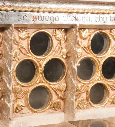 Zdjęcie nr 25: Nastawa jednoosiowa, jednokondygnacyjna ze zwieńczeniem, na wysokim dwustrefowym cokole z wyodrębnionymi czterema prostopadłościanami. Ołtarz kamienny, prostopadłościenny, z kamienną mensą. Antepedium ujęte srebrzoną opaską z napisem „kości ich niech wypuszczą pędu ze swego miejsca, aby byli wsławieni przez swoich synów”, pole podzielone na cztery części ornamentem roślinnym, każda wypełniona złoconą wicią kwiatową i czterema okrągłymi prześwitami. Na ołtarzu ustawione tabernakulum w formie Arki Przymierza. Nastawa ujęta dwiema parami pilastrów i dwiema parami kolumn o kręconych trzonach ustawionych pod kątem na zewnątrz, dźwigającymi pełne belkowanie z kostkowaniem, wyłamane na ich osi, przerwane nad polem środkowym oraz fragmenty przerwanego, półkolistego przyczółka. W polu środkowym wnęka w formie stojącego prostokąta zamkniętego łukiem półkolistym, w niej mniejszy obraz w kształcie stojącego prostokąta zamkniętego łukiem półkolistym nadwieszonym z przedstawieniem Wizji św. Franciszka, ujęty ramą dekorowaną rocaille&#039;em. Zwieńczenie w formie grupy rzeźbiarskiej Przemienienia Pańskiego na tle obłoków i w glorii promienistej. 
W partii belkowania nad polem głównym, na rzeźbionej skale podtrzymywanej przez rocaille klęczące postacie św. Piotra, św. Jana i św. Jakuba w dynamicznych pozach. Nad nimi unosi się Chrystus w otoku z obłoków i glorii, flankowany przez figury Mojżesza i Eliasza klęczące na przerwanym przyczółku, za nimi nadlatujące putta na obłokach. Po lewej stronie Piotr klęczący frontalnie z uniesionymi rękami. Obok niego klęczący św. Jan zwrócony profilem w lewo, z rękami wyciągniętymi w przód, o młodzieńczych rysach i długich, kręconych włosach. Święty Jakub po prawej stronie, w pozycji siedzącej, zwrócony w trzech czwartych w prawo z rękami wyciągniętymi w lewo. Wszyscy ubrani w przylegające do ciała tuniki oraz płaszcze przepasane w partii nóg. Nad nimi Chrystus w pozycji stojącej, frontalnie, w kontrapoście, z uniesioną głową i rękami rozłożonymi na boki, ubrany jest w tunikę oraz płaszcz przewiązany przez lewe ramię i wokół nóg. Na lewym fragmencie przyczółka klęczy Eliasz, zwrócony w trzech czwartych w lewo, pochylony, prawą ręką przytrzymuje na boku księgę, lewą wyciąga w przód. Ubrany jest w tunikę oraz rozwiany płaszcz. Na prawym fragmencie przyczółka klęczy Mojżesz, zwrócony w trzech czwartych w prawo, z pochylona głową, obiema rękami trzyma tablice przykazań. Ubrany jest w tunikę o krótkich rękawach oraz płaszcz zawinięty na lewym ramieniu i opadający na nogi. Obaj prorocy ukazani jako starcy. Nastawa flankowana dwoma wspornikami z figurami św. Wacława i św. Floriana. Struktura polichromowana w kolorze beżowym z żółtymi detalami oraz złoconymi profilami, ornamentyką i zwieńczeniem. Figury w partii ciała polichromowane naturalistycznie z brązowymi włosami i brodami oraz złoconymi szatami i atrybutami. 

