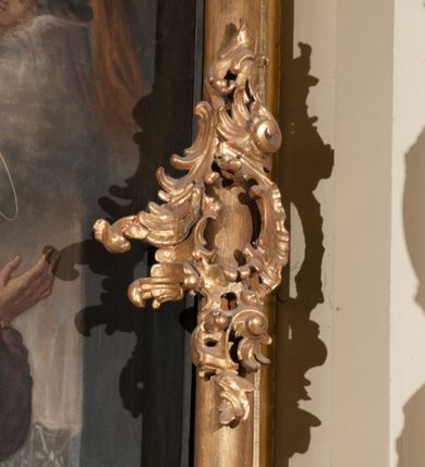 Zdjęcie nr 12: Obraz klęczącego przed ołtarzem św. Franciszka, któremu ukazuje się siedzący w chmurach Jezus i Maria w otoczeniu aniołów. Maria zwrócona w trzech czwartych w lewo, ukazana w różowej sukni, niebieskim płaszczu i z białym welonem na głowie oraz wieńcem z gwiazd. Prawa ręka wyciągnięta w stronę świętego, lewa przyłożona do piersi. Chrystus o długich, brązowych włosach i krótkim zaroście, ukazany frontalnie, w białej luźniej szacie i czerwonym płaszczu spiętym broszą i z krzyżowym promienistym nimbem nad głową. Lewa ręka lekko uniesiona do góry, prawa spoczywa na kolanie. Święty Franciszek ukazany tyłem do widza, z twarzą z profilu, uniesioną w stronę Marii, z rozłożonymi rękoma. Ubrany w brązowy habit franciszkański, przepasany podwójnym sznurem. Wokół Marii i Jezusa aniołowie w różnych pozach i główki aniołów. 