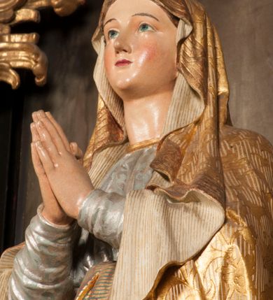 Zdjęcie nr 99: Tabernakulum w formie Arki Przymierza, adorowanej przez dwie klęczące figury starotestamentowego arcykapłana i biskupa oraz dwie stojące postacie lewitów oraz klęczące aniołów, zwieńczonej glorią promienistą z okiem Opatrzności. Wsparte na ośmiu cylindrycznych nóżkach prostopadłościenne tabernakulum jest od frontu podzielone na trzy pola wyznaczone kanelowanymi listwami. Pole środkowe stanowią drzwiczki z rytymi cyframi Dekalogu z ukrzyżowanym Chrystusem, pola boczne z wiązką pałek wodnych z jednej i winnym gronem z drugiej strony. Na skłębionych chmurach z podestem leży Baranek (obecnie w jego miejscu znajduje się figura Matki Boskiej). W tle znacznej wielkości gloria promienista z wieńcem chmur i umieszczonym w nim okiem Opatrzności oraz dwie uskrzydlone główki, nad którymi papieska tiara ze skrzyżowanymi kluczami. Po bokach Baranka dwa klęczące, uskrzydlone nagie aniołki. Obok tabernakulum dwie klęczące postacie z kadzielnicami w rękach. Postać po lewej w stroju biskupim, w albie, stule i kapie oraz infule z dwiema taśmami. Postać po prawej stronie jest ubrany w tradycyjny starotestamentowy strój – efod czyli tunikę i płaszcz wierzchni przepasany na biodrach, pektorał na piersi i zawój na głowie. Za nimi dwaj stojący lewici w tunikach przepasanych na biodrach i wysokich butach. Adorujące Baranka anioły w pozycji klęczącej z rękami skrzyżowanymi na piersi, ze skrzydłami na plecach i nogami w połowie utworzonymi ze skrzydeł.  


