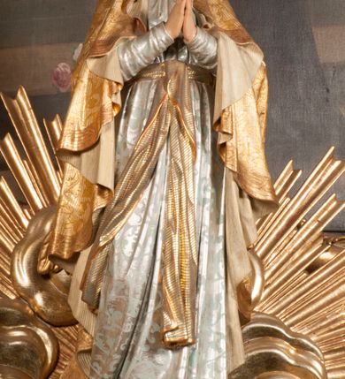 Zdjęcie nr 98: Tabernakulum w formie Arki Przymierza, adorowanej przez dwie klęczące figury starotestamentowego arcykapłana i biskupa oraz dwie stojące postacie lewitów oraz klęczące aniołów, zwieńczonej glorią promienistą z okiem Opatrzności. Wsparte na ośmiu cylindrycznych nóżkach prostopadłościenne tabernakulum jest od frontu podzielone na trzy pola wyznaczone kanelowanymi listwami. Pole środkowe stanowią drzwiczki z rytymi cyframi Dekalogu z ukrzyżowanym Chrystusem, pola boczne z wiązką pałek wodnych z jednej i winnym gronem z drugiej strony. Na skłębionych chmurach z podestem leży Baranek (obecnie w jego miejscu znajduje się figura Matki Boskiej). W tle znacznej wielkości gloria promienista z wieńcem chmur i umieszczonym w nim okiem Opatrzności oraz dwie uskrzydlone główki, nad którymi papieska tiara ze skrzyżowanymi kluczami. Po bokach Baranka dwa klęczące, uskrzydlone nagie aniołki. Obok tabernakulum dwie klęczące postacie z kadzielnicami w rękach. Postać po lewej w stroju biskupim, w albie, stule i kapie oraz infule z dwiema taśmami. Postać po prawej stronie jest ubrany w tradycyjny starotestamentowy strój – efod czyli tunikę i płaszcz wierzchni przepasany na biodrach, pektorał na piersi i zawój na głowie. Za nimi dwaj stojący lewici w tunikach przepasanych na biodrach i wysokich butach. Adorujące Baranka anioły w pozycji klęczącej z rękami skrzyżowanymi na piersi, ze skrzydłami na plecach i nogami w połowie utworzonymi ze skrzydeł.  


