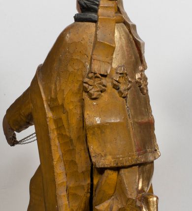 Zdjęcie nr 8: Tabernakulum w formie Arki Przymierza, adorowanej przez dwie klęczące figury starotestamentowego arcykapłana i biskupa oraz dwie stojące postacie lewitów oraz klęczące aniołów, zwieńczonej glorią promienistą z okiem Opatrzności. Wsparte na ośmiu cylindrycznych nóżkach prostopadłościenne tabernakulum jest od frontu podzielone na trzy pola wyznaczone kanelowanymi listwami. Pole środkowe stanowią drzwiczki z rytymi cyframi Dekalogu z ukrzyżowanym Chrystusem, pola boczne z wiązką pałek wodnych z jednej i winnym gronem z drugiej strony. Na skłębionych chmurach z podestem leży Baranek (obecnie w jego miejscu znajduje się figura Matki Boskiej). W tle znacznej wielkości gloria promienista z wieńcem chmur i umieszczonym w nim okiem Opatrzności oraz dwie uskrzydlone główki, nad którymi papieska tiara ze skrzyżowanymi kluczami. Po bokach Baranka dwa klęczące, uskrzydlone nagie aniołki. Obok tabernakulum dwie klęczące postacie z kadzielnicami w rękach. Postać po lewej w stroju biskupim, w albie, stule i kapie oraz infule z dwiema taśmami. Postać po prawej stronie jest ubrany w tradycyjny starotestamentowy strój – efod czyli tunikę i płaszcz wierzchni przepasany na biodrach, pektorał na piersi i zawój na głowie. Za nimi dwaj stojący lewici w tunikach przepasanych na biodrach i wysokich butach. Adorujące Baranka anioły w pozycji klęczącej z rękami skrzyżowanymi na piersi, ze skrzydłami na plecach i nogami w połowie utworzonymi ze skrzydeł.  


