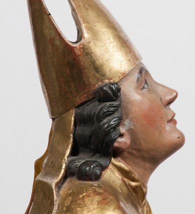 Zdjęcie nr 10: Tabernakulum w formie Arki Przymierza, adorowanej przez dwie klęczące figury starotestamentowego arcykapłana i biskupa oraz dwie stojące postacie lewitów oraz klęczące aniołów, zwieńczonej glorią promienistą z okiem Opatrzności. Wsparte na ośmiu cylindrycznych nóżkach prostopadłościenne tabernakulum jest od frontu podzielone na trzy pola wyznaczone kanelowanymi listwami. Pole środkowe stanowią drzwiczki z rytymi cyframi Dekalogu z ukrzyżowanym Chrystusem, pola boczne z wiązką pałek wodnych z jednej i winnym gronem z drugiej strony. Na skłębionych chmurach z podestem leży Baranek (obecnie w jego miejscu znajduje się figura Matki Boskiej). W tle znacznej wielkości gloria promienista z wieńcem chmur i umieszczonym w nim okiem Opatrzności oraz dwie uskrzydlone główki, nad którymi papieska tiara ze skrzyżowanymi kluczami. Po bokach Baranka dwa klęczące, uskrzydlone nagie aniołki. Obok tabernakulum dwie klęczące postacie z kadzielnicami w rękach. Postać po lewej w stroju biskupim, w albie, stule i kapie oraz infule z dwiema taśmami. Postać po prawej stronie jest ubrany w tradycyjny starotestamentowy strój – efod czyli tunikę i płaszcz wierzchni przepasany na biodrach, pektorał na piersi i zawój na głowie. Za nimi dwaj stojący lewici w tunikach przepasanych na biodrach i wysokich butach. Adorujące Baranka anioły w pozycji klęczącej z rękami skrzyżowanymi na piersi, ze skrzydłami na plecach i nogami w połowie utworzonymi ze skrzydeł.  


