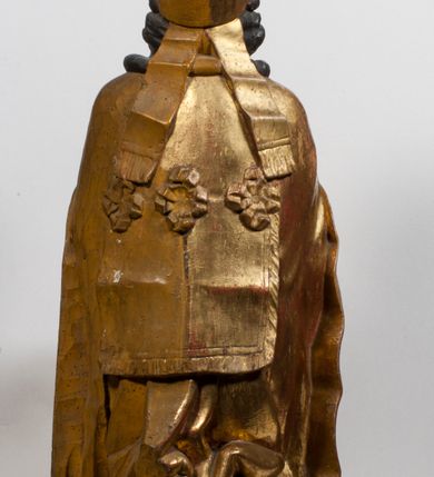 Zdjęcie nr 9: Tabernakulum w formie Arki Przymierza, adorowanej przez dwie klęczące figury starotestamentowego arcykapłana i biskupa oraz dwie stojące postacie lewitów oraz klęczące aniołów, zwieńczonej glorią promienistą z okiem Opatrzności. Wsparte na ośmiu cylindrycznych nóżkach prostopadłościenne tabernakulum jest od frontu podzielone na trzy pola wyznaczone kanelowanymi listwami. Pole środkowe stanowią drzwiczki z rytymi cyframi Dekalogu z ukrzyżowanym Chrystusem, pola boczne z wiązką pałek wodnych z jednej i winnym gronem z drugiej strony. Na skłębionych chmurach z podestem leży Baranek (obecnie w jego miejscu znajduje się figura Matki Boskiej). W tle znacznej wielkości gloria promienista z wieńcem chmur i umieszczonym w nim okiem Opatrzności oraz dwie uskrzydlone główki, nad którymi papieska tiara ze skrzyżowanymi kluczami. Po bokach Baranka dwa klęczące, uskrzydlone nagie aniołki. Obok tabernakulum dwie klęczące postacie z kadzielnicami w rękach. Postać po lewej w stroju biskupim, w albie, stule i kapie oraz infule z dwiema taśmami. Postać po prawej stronie jest ubrany w tradycyjny starotestamentowy strój – efod czyli tunikę i płaszcz wierzchni przepasany na biodrach, pektorał na piersi i zawój na głowie. Za nimi dwaj stojący lewici w tunikach przepasanych na biodrach i wysokich butach. Adorujące Baranka anioły w pozycji klęczącej z rękami skrzyżowanymi na piersi, ze skrzydłami na plecach i nogami w połowie utworzonymi ze skrzydeł.  


