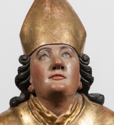 Zdjęcie nr 17: Tabernakulum w formie Arki Przymierza, adorowanej przez dwie klęczące figury starotestamentowego arcykapłana i biskupa oraz dwie stojące postacie lewitów oraz klęczące aniołów, zwieńczonej glorią promienistą z okiem Opatrzności. Wsparte na ośmiu cylindrycznych nóżkach prostopadłościenne tabernakulum jest od frontu podzielone na trzy pola wyznaczone kanelowanymi listwami. Pole środkowe stanowią drzwiczki z rytymi cyframi Dekalogu z ukrzyżowanym Chrystusem, pola boczne z wiązką pałek wodnych z jednej i winnym gronem z drugiej strony. Na skłębionych chmurach z podestem leży Baranek (obecnie w jego miejscu znajduje się figura Matki Boskiej). W tle znacznej wielkości gloria promienista z wieńcem chmur i umieszczonym w nim okiem Opatrzności oraz dwie uskrzydlone główki, nad którymi papieska tiara ze skrzyżowanymi kluczami. Po bokach Baranka dwa klęczące, uskrzydlone nagie aniołki. Obok tabernakulum dwie klęczące postacie z kadzielnicami w rękach. Postać po lewej w stroju biskupim, w albie, stule i kapie oraz infule z dwiema taśmami. Postać po prawej stronie jest ubrany w tradycyjny starotestamentowy strój – efod czyli tunikę i płaszcz wierzchni przepasany na biodrach, pektorał na piersi i zawój na głowie. Za nimi dwaj stojący lewici w tunikach przepasanych na biodrach i wysokich butach. Adorujące Baranka anioły w pozycji klęczącej z rękami skrzyżowanymi na piersi, ze skrzydłami na plecach i nogami w połowie utworzonymi ze skrzydeł.  


