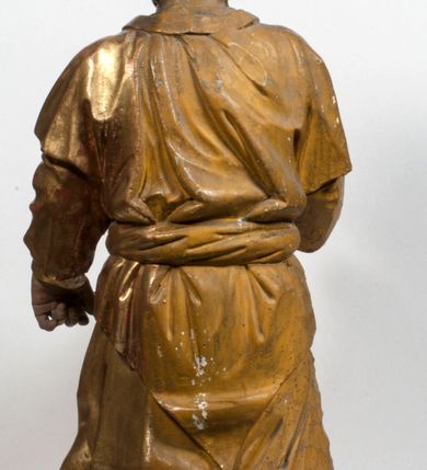 Zdjęcie nr 27: Tabernakulum w formie Arki Przymierza, adorowanej przez dwie klęczące figury starotestamentowego arcykapłana i biskupa oraz dwie stojące postacie lewitów oraz klęczące aniołów, zwieńczonej glorią promienistą z okiem Opatrzności. Wsparte na ośmiu cylindrycznych nóżkach prostopadłościenne tabernakulum jest od frontu podzielone na trzy pola wyznaczone kanelowanymi listwami. Pole środkowe stanowią drzwiczki z rytymi cyframi Dekalogu z ukrzyżowanym Chrystusem, pola boczne z wiązką pałek wodnych z jednej i winnym gronem z drugiej strony. Na skłębionych chmurach z podestem leży Baranek (obecnie w jego miejscu znajduje się figura Matki Boskiej). W tle znacznej wielkości gloria promienista z wieńcem chmur i umieszczonym w nim okiem Opatrzności oraz dwie uskrzydlone główki, nad którymi papieska tiara ze skrzyżowanymi kluczami. Po bokach Baranka dwa klęczące, uskrzydlone nagie aniołki. Obok tabernakulum dwie klęczące postacie z kadzielnicami w rękach. Postać po lewej w stroju biskupim, w albie, stule i kapie oraz infule z dwiema taśmami. Postać po prawej stronie jest ubrany w tradycyjny starotestamentowy strój – efod czyli tunikę i płaszcz wierzchni przepasany na biodrach, pektorał na piersi i zawój na głowie. Za nimi dwaj stojący lewici w tunikach przepasanych na biodrach i wysokich butach. Adorujące Baranka anioły w pozycji klęczącej z rękami skrzyżowanymi na piersi, ze skrzydłami na plecach i nogami w połowie utworzonymi ze skrzydeł.  


