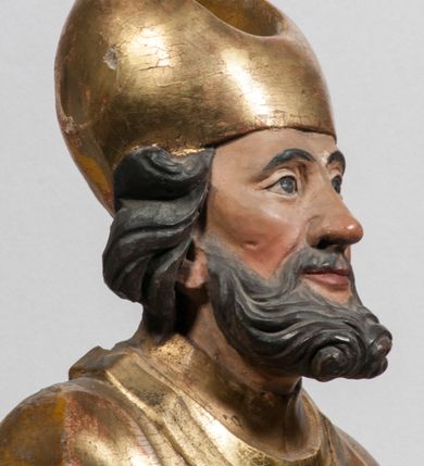 Zdjęcie nr 33: Tabernakulum w formie Arki Przymierza, adorowanej przez dwie klęczące figury starotestamentowego arcykapłana i biskupa oraz dwie stojące postacie lewitów oraz klęczące aniołów, zwieńczonej glorią promienistą z okiem Opatrzności. Wsparte na ośmiu cylindrycznych nóżkach prostopadłościenne tabernakulum jest od frontu podzielone na trzy pola wyznaczone kanelowanymi listwami. Pole środkowe stanowią drzwiczki z rytymi cyframi Dekalogu z ukrzyżowanym Chrystusem, pola boczne z wiązką pałek wodnych z jednej i winnym gronem z drugiej strony. Na skłębionych chmurach z podestem leży Baranek (obecnie w jego miejscu znajduje się figura Matki Boskiej). W tle znacznej wielkości gloria promienista z wieńcem chmur i umieszczonym w nim okiem Opatrzności oraz dwie uskrzydlone główki, nad którymi papieska tiara ze skrzyżowanymi kluczami. Po bokach Baranka dwa klęczące, uskrzydlone nagie aniołki. Obok tabernakulum dwie klęczące postacie z kadzielnicami w rękach. Postać po lewej w stroju biskupim, w albie, stule i kapie oraz infule z dwiema taśmami. Postać po prawej stronie jest ubrany w tradycyjny starotestamentowy strój – efod czyli tunikę i płaszcz wierzchni przepasany na biodrach, pektorał na piersi i zawój na głowie. Za nimi dwaj stojący lewici w tunikach przepasanych na biodrach i wysokich butach. Adorujące Baranka anioły w pozycji klęczącej z rękami skrzyżowanymi na piersi, ze skrzydłami na plecach i nogami w połowie utworzonymi ze skrzydeł.  


