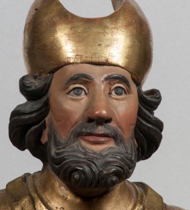 Zdjęcie nr 36: Tabernakulum w formie Arki Przymierza, adorowanej przez dwie klęczące figury starotestamentowego arcykapłana i biskupa oraz dwie stojące postacie lewitów oraz klęczące aniołów, zwieńczonej glorią promienistą z okiem Opatrzności. Wsparte na ośmiu cylindrycznych nóżkach prostopadłościenne tabernakulum jest od frontu podzielone na trzy pola wyznaczone kanelowanymi listwami. Pole środkowe stanowią drzwiczki z rytymi cyframi Dekalogu z ukrzyżowanym Chrystusem, pola boczne z wiązką pałek wodnych z jednej i winnym gronem z drugiej strony. Na skłębionych chmurach z podestem leży Baranek (obecnie w jego miejscu znajduje się figura Matki Boskiej). W tle znacznej wielkości gloria promienista z wieńcem chmur i umieszczonym w nim okiem Opatrzności oraz dwie uskrzydlone główki, nad którymi papieska tiara ze skrzyżowanymi kluczami. Po bokach Baranka dwa klęczące, uskrzydlone nagie aniołki. Obok tabernakulum dwie klęczące postacie z kadzielnicami w rękach. Postać po lewej w stroju biskupim, w albie, stule i kapie oraz infule z dwiema taśmami. Postać po prawej stronie jest ubrany w tradycyjny starotestamentowy strój – efod czyli tunikę i płaszcz wierzchni przepasany na biodrach, pektorał na piersi i zawój na głowie. Za nimi dwaj stojący lewici w tunikach przepasanych na biodrach i wysokich butach. Adorujące Baranka anioły w pozycji klęczącej z rękami skrzyżowanymi na piersi, ze skrzydłami na plecach i nogami w połowie utworzonymi ze skrzydeł.  


