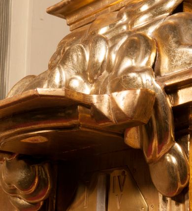 Zdjęcie nr 66: Tabernakulum w formie Arki Przymierza, adorowanej przez dwie klęczące figury starotestamentowego arcykapłana i biskupa oraz dwie stojące postacie lewitów oraz klęczące aniołów, zwieńczonej glorią promienistą z okiem Opatrzności. Wsparte na ośmiu cylindrycznych nóżkach prostopadłościenne tabernakulum jest od frontu podzielone na trzy pola wyznaczone kanelowanymi listwami. Pole środkowe stanowią drzwiczki z rytymi cyframi Dekalogu z ukrzyżowanym Chrystusem, pola boczne z wiązką pałek wodnych z jednej i winnym gronem z drugiej strony. Na skłębionych chmurach z podestem leży Baranek (obecnie w jego miejscu znajduje się figura Matki Boskiej). W tle znacznej wielkości gloria promienista z wieńcem chmur i umieszczonym w nim okiem Opatrzności oraz dwie uskrzydlone główki, nad którymi papieska tiara ze skrzyżowanymi kluczami. Po bokach Baranka dwa klęczące, uskrzydlone nagie aniołki. Obok tabernakulum dwie klęczące postacie z kadzielnicami w rękach. Postać po lewej w stroju biskupim, w albie, stule i kapie oraz infule z dwiema taśmami. Postać po prawej stronie jest ubrany w tradycyjny starotestamentowy strój – efod czyli tunikę i płaszcz wierzchni przepasany na biodrach, pektorał na piersi i zawój na głowie. Za nimi dwaj stojący lewici w tunikach przepasanych na biodrach i wysokich butach. Adorujące Baranka anioły w pozycji klęczącej z rękami skrzyżowanymi na piersi, ze skrzydłami na plecach i nogami w połowie utworzonymi ze skrzydeł.  


