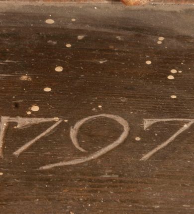Zdjęcie nr 68: Tabernakulum w formie Arki Przymierza, adorowanej przez dwie klęczące figury starotestamentowego arcykapłana i biskupa oraz dwie stojące postacie lewitów oraz klęczące aniołów, zwieńczonej glorią promienistą z okiem Opatrzności. Wsparte na ośmiu cylindrycznych nóżkach prostopadłościenne tabernakulum jest od frontu podzielone na trzy pola wyznaczone kanelowanymi listwami. Pole środkowe stanowią drzwiczki z rytymi cyframi Dekalogu z ukrzyżowanym Chrystusem, pola boczne z wiązką pałek wodnych z jednej i winnym gronem z drugiej strony. Na skłębionych chmurach z podestem leży Baranek (obecnie w jego miejscu znajduje się figura Matki Boskiej). W tle znacznej wielkości gloria promienista z wieńcem chmur i umieszczonym w nim okiem Opatrzności oraz dwie uskrzydlone główki, nad którymi papieska tiara ze skrzyżowanymi kluczami. Po bokach Baranka dwa klęczące, uskrzydlone nagie aniołki. Obok tabernakulum dwie klęczące postacie z kadzielnicami w rękach. Postać po lewej w stroju biskupim, w albie, stule i kapie oraz infule z dwiema taśmami. Postać po prawej stronie jest ubrany w tradycyjny starotestamentowy strój – efod czyli tunikę i płaszcz wierzchni przepasany na biodrach, pektorał na piersi i zawój na głowie. Za nimi dwaj stojący lewici w tunikach przepasanych na biodrach i wysokich butach. Adorujące Baranka anioły w pozycji klęczącej z rękami skrzyżowanymi na piersi, ze skrzydłami na plecach i nogami w połowie utworzonymi ze skrzydeł.  



