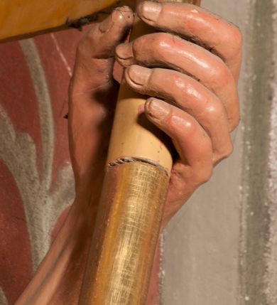 Zdjęcie nr 20: Rzeźba zwrócona w trzech czwartych w prawo, z uniesioną głową, o esowato wygiętej sylwetce, lewą nogę opiera na fragmencie płaszcza. Święty Florian w lewej uniesionej ręce trzyma drzewce rozwianej chorągwi z wizerunkiem orła w koronie, prawą wylewa z dzbana wodę na płonący budynek kościoła stojący przy jego prawej nodze. Twarz ma szczupłą, o dużych, głęboko rzeźbionych oczach, skierowanych w górę i uniesionych, zmarszczonych brwiach, dużym, lekko garbatym i zadartym nosie oraz rozchylonych ustach, okoloną krótką, silnie kręconą brodą oraz rozwianymi na boki włosami. Ubrany jest w krótką tunikę oraz zbroję torsową, przez biodra ma przewiązany pas z zawieszonym przy lewym boku mieczem. Przez lewe ramię ma zawiązany diagonalnie płaszcz, opadający na prawe przedramię oraz zawinięty na lewe udo. Na głowie ma hełm dekorowany maszkaronem z pióropuszem, a na nogach wysokie buty. Polichromia ciała naturalistyczna, włosy brązowe, strój i atrybuty złocone, detale srebrzone. 

