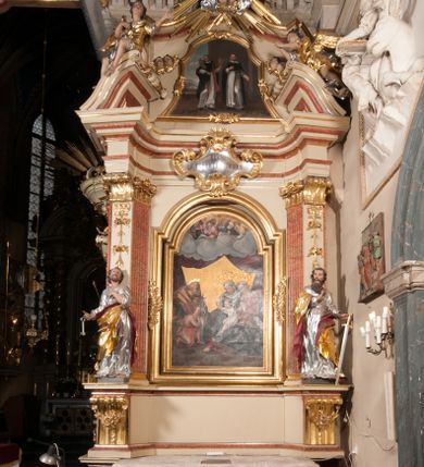 Zdjęcie nr 1: Nastawa architektoniczna, jednoosiowa, jednokondygnacyjna, ze zwieńczeniem, ustawiona na dwustrefowym cokole z wyodrębnionymi prostopadłościanami i konsolami. Ołtarz kamienny, prostopadłościenny, z kamienną mensą z portatylem. Antepedium kamienne, ujęte opaską, z rzeźbionymi maswerkami w polu. Nastawa flankowana parą opilastrowanych filarów, o kanelowanych trzonach i kapitelach kompozytowych, ustawionych pod kątem na zewnątrz, dekorowanych kwiatowymi zwisami, dźwigających pełne belkowanie wyłamane na ich osi oraz fragmenty falistego, przerwanego przyczółka z figurami aniołów. Na tle filarów ustawione figury św. Piotra i św. Pawła. Niemal całe pole główne wypełnione wnęką w formie stojącego prostokąta zamkniętego łukiem półkolistym nadwieszonym ujętą profilowaną ramą dekorowaną rocaille&#039;m, z mniejszym obrazem Rodziny Marii ze św. Janem Chrzcicielem, w osobnej, profilowanej ramie. Nad nim, w partii belkowania rocaille&#039;owy kartusz z napisem „REGNI / ET PROTECTORIBUS”. Zwieńczenie w formie leżącego prostokąta zamkniętego fragmentem falistego gzymsu. W polu obraz św. Jacka i bł. Czesława w kształcie trapezu o wklęsłych bokach, zamkniętego łukiem segmentowym nadwieszonym, ujęty ramą; flankowany dwiema parami uskrzydlonych główek anielskich. Zwieńczenie zamknięte medalionem z napisem „CHRISTI / FAMILIAE” w otoku z obłoków i uskrzydlonych główek anielskich, w glorii promienistej. Nastawa polichromowana w kolorze beżowym z detalami malowanymi na sposób imitujący jasnoróżowy marmur, ornamentyka i profile złocone. 
