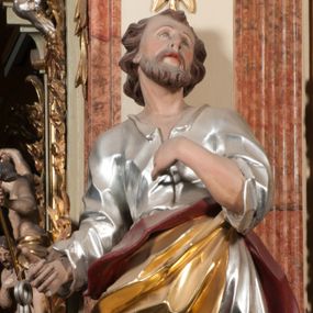 Zdjęcie nr 1: Rzeźba drążona z tyłu, ustawiona na niskiej podstawie. Figura ukazana frontalnie, z uniesioną głową, skierowaną w lewo, w kontrapoście, o esowato wygiętej sylwetce. Prawą dłoń z kluczami wyciąga w bok, lewą kładzie na piersi. Twarz pociągła o migdałowatych, blisko siebie umieszczonych oczach, lekko garbatym nosie i wąskich, rozchylonych ustach. Okolona jest krótką brodą oraz brązowymi, kręconymi włosami. Piotr ubrany jest w srebrzoną tunikę, przepasaną w talii, z kołnierzykiem oraz płaszcz przepasany w partii nóg, zawiązany na lewym biodrze, złocony o czerwonej podszewce. Polichromia ciała naturalistyczna. 
