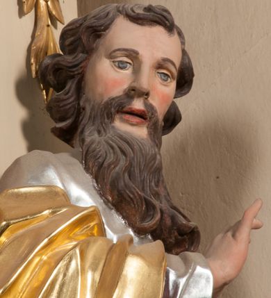 Zdjęcie nr 8: Figura drążona z tyłu, ustawiona na nieregularnej podstawie. Święty zwrócony frontalnie, z głową skierowaną w prawo, w kontrapoście, o esowato wygiętej sylwetce. W lewej, wyciągniętej w bok ręce trzyma miecz skierowany ostrzem w dół, prawą, ugiętą, unosi na tle piersi. Twarz ma pociągłą, o migdałowatych, blisko siebie osadzonych oczach, lekko garbatym nosie oraz pełnych, rozchylonych ustach. Okolona jest długą, falowaną brodą, opadającą na pierś oraz krótkimi, kręconymi, brązowymi włosami. Ubrany jest w srebrzoną tunikę, przepasaną w talii oraz złocony płaszcz z czerwoną podszewką, zarzucony na prawe ramię i opadający na lewa nogę. Polichromia ciała naturalistyczna.

