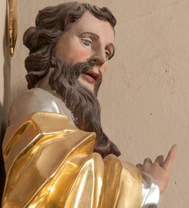 Zdjęcie nr 7: Figura drążona z tyłu, ustawiona na nieregularnej podstawie. Święty zwrócony frontalnie, z głową skierowaną w prawo, w kontrapoście, o esowato wygiętej sylwetce. W lewej, wyciągniętej w bok ręce trzyma miecz skierowany ostrzem w dół, prawą, ugiętą, unosi na tle piersi. Twarz ma pociągłą, o migdałowatych, blisko siebie osadzonych oczach, lekko garbatym nosie oraz pełnych, rozchylonych ustach. Okolona jest długą, falowaną brodą, opadającą na pierś oraz krótkimi, kręconymi, brązowymi włosami. Ubrany jest w srebrzoną tunikę, przepasaną w talii oraz złocony płaszcz z czerwoną podszewką, zarzucony na prawe ramię i opadający na lewa nogę. Polichromia ciała naturalistyczna.

