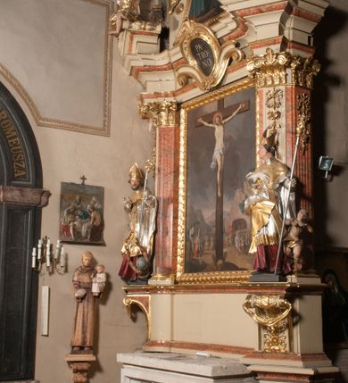 Zdjęcie nr 4: Nastawa architektoniczna, jednoosiowa, jednokondygnacyjna, ze zwieńczeniem, ustawiona na dwustrefowym cokole z wyodrębnionymi prostopadłościanami i konsolami. Ołtarz kamienny, prostopadłościenny, z kamienną mensą. Antepedium kamienne, ujęte opaską, podzielone dwoma kolumienkami na cokołach na trzy pola, każde wypełnione płaskorzeźbionymi kwiatami i prześwitami. Nastawa flankowana parą opilastrowanych filarów, o kanelowanych trzonach o kapitelach kompozytowych, ustawionych pod kątem na zewnątrz, dekorowanych kwiatowymi zwisami, dźwigających pełne belkowanie wyłamane na ich osi oraz fragmenty falistego, przerwanego przyczółka z figurami aniołów. Na tle filarów ustawione figury św. Stanisława i św. Wojciecha. Całe pole główne wypełnione wnęką w formie stojącego prostokąta ujętego ramą dekorowaną ornamentem geometrycznym, z obrazem Ukrzyżowania. Nad nim, w partii belkowania wolutowy kartusz z napisem „PA=/TRO=/NO”. Zwieńczenie w formie leżącego prostokąta zamkniętego fragmentem falistego gzymsu. W polu obraz św. Kingi w kształcie trapezu o wklęsłych bokach, zamkniętego łukiem segmentowym nadwieszonym, ujęty ramą; flankowany dwiema uskrzydlonymi główkami anielskimi. Zwieńczenie zamknięte wolutowym kartuszem przeplatanym tkaniną z napisem „RE=GNI”. Nastawa polichromowana w kolorze beżowym z detalami malowanymi na sposób imitujący jasnoróżowy marmur, ornamentyka i profile złocone. 
